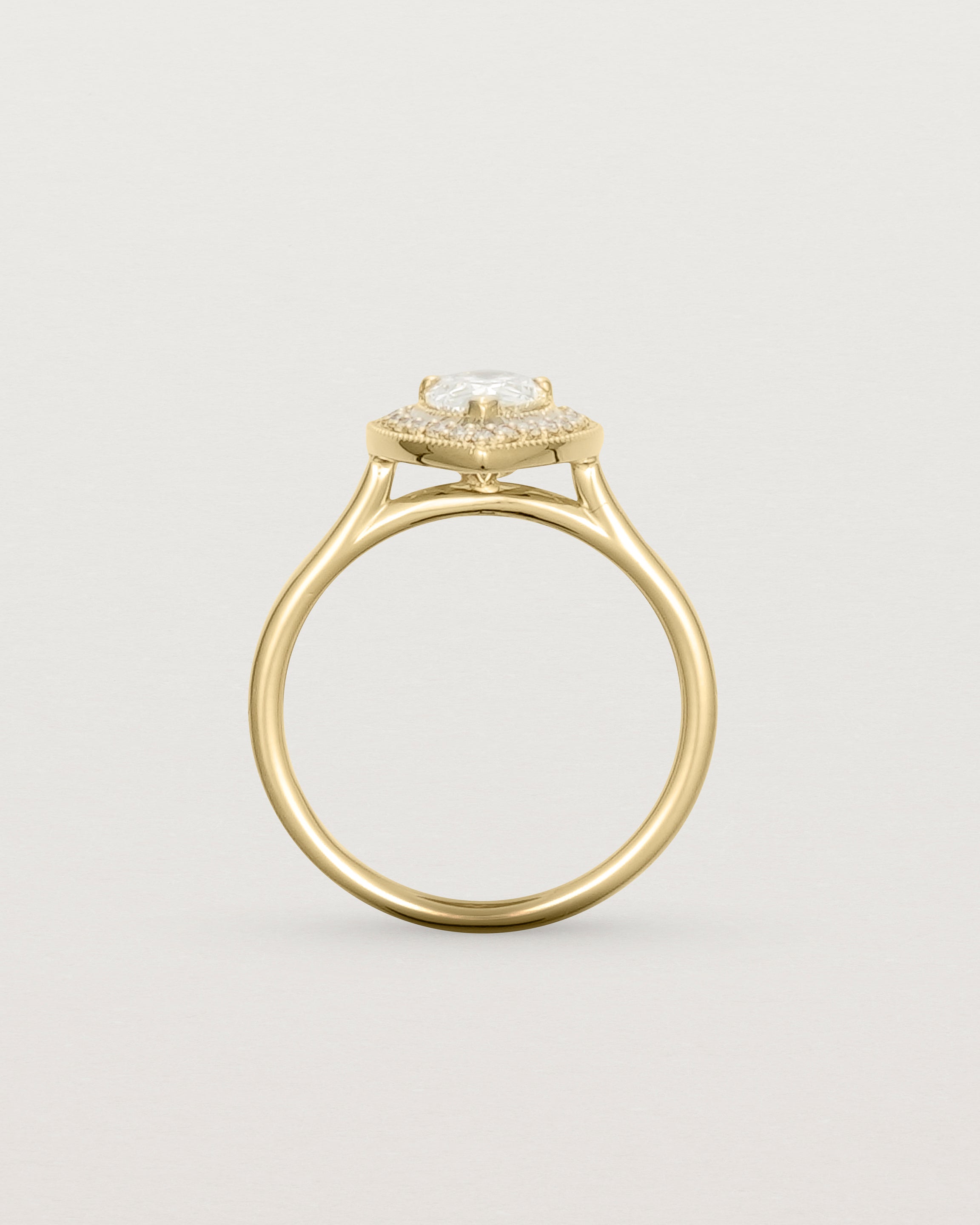 Standing view pear halo ring featuring a pear cut clear laboratory grown diamond and a halo of white diamonds in yellow gold