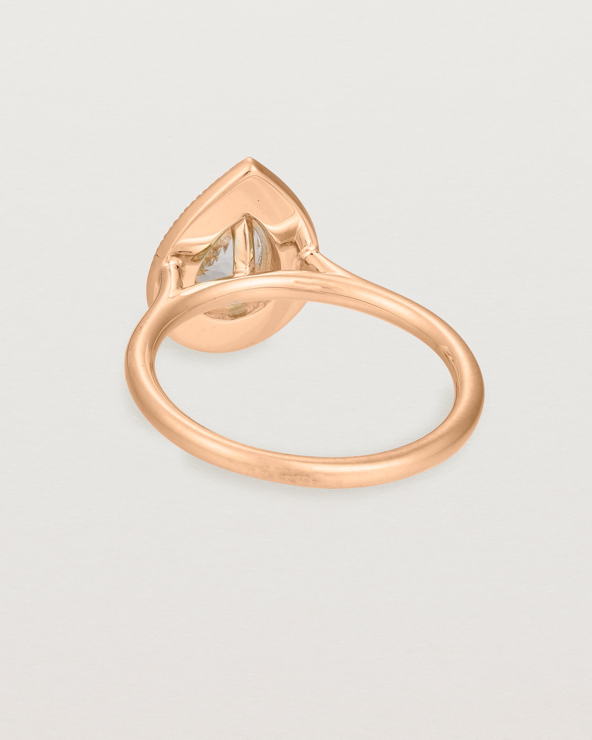 Back view pear halo ring featuring a pear cut pale pink morganite and a halo of white diamonds in rose gold