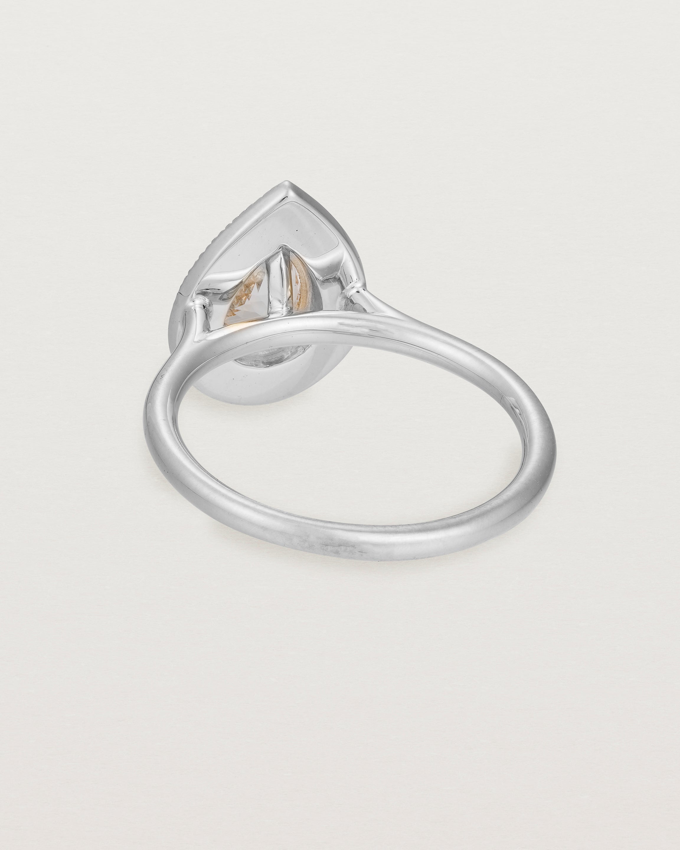 Back view pear halo ring featuring a pear cut pale pink morganite and a halo of white diamonds in white gold