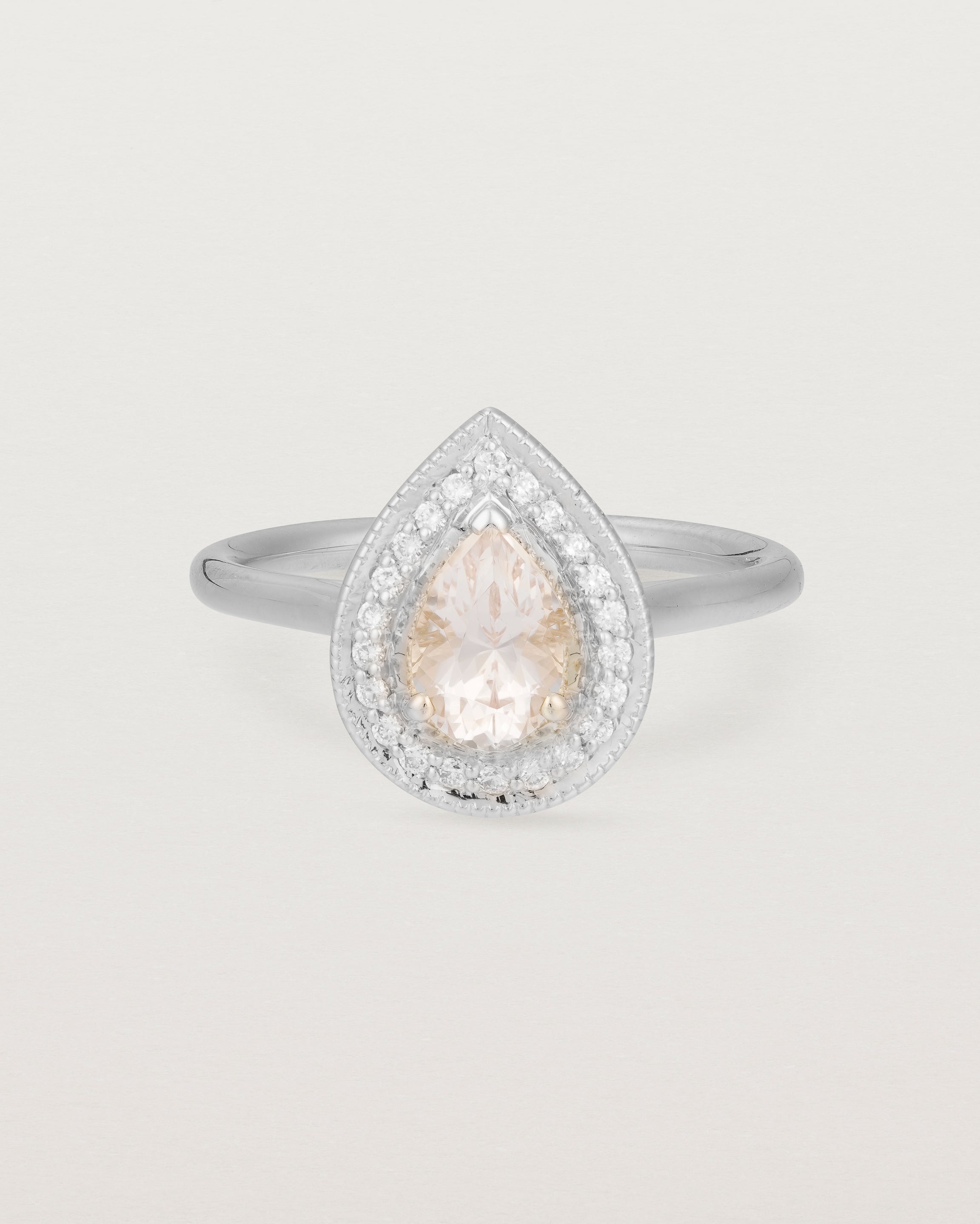 Front view pear halo ring featuring a pear cut pale pink morganite and a halo of white diamonds in white gold