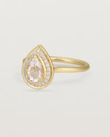 Side view pear halo ring featuring a pear cut pale pink morganite and a halo of white diamonds in yellow gold