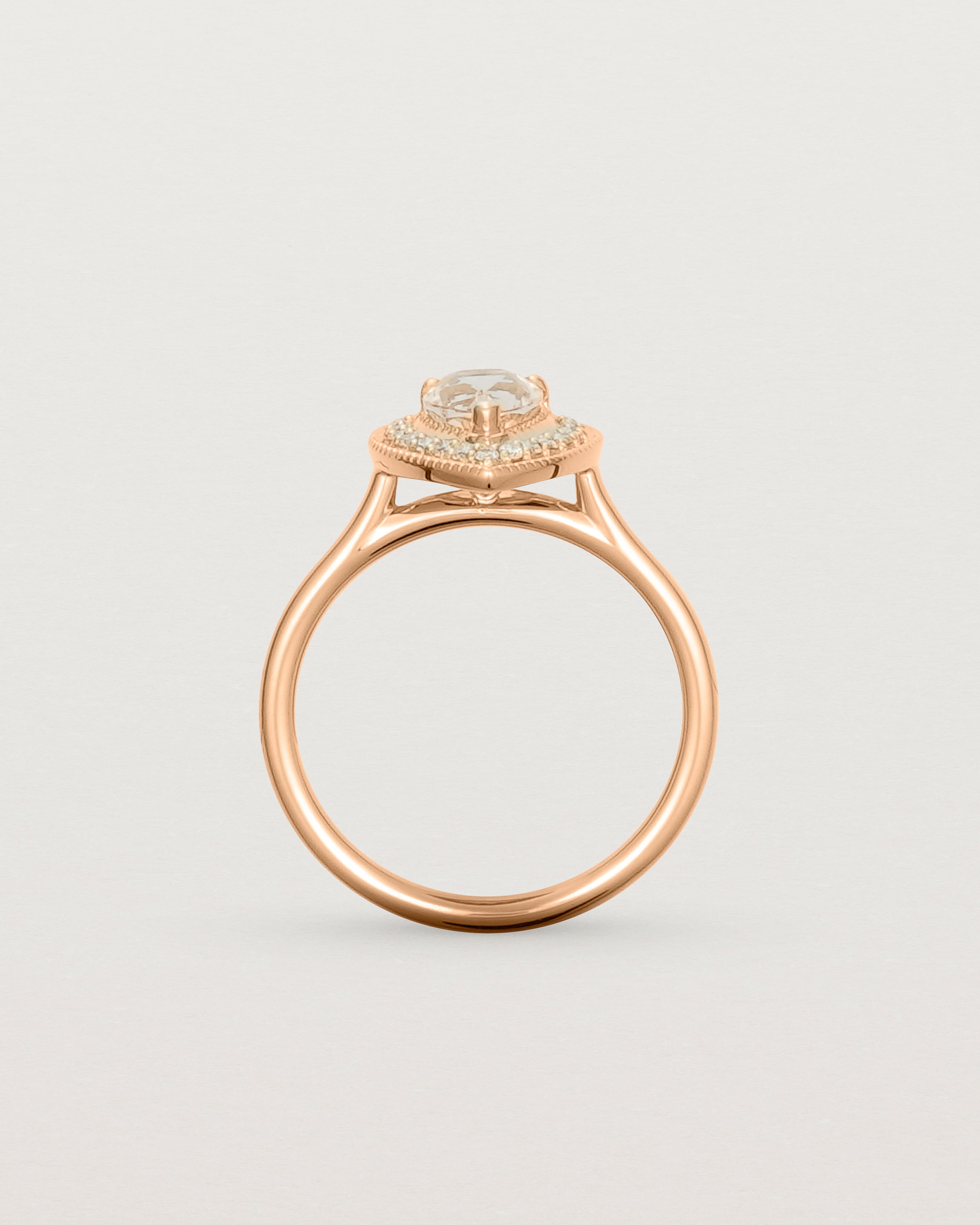 Standing view pear halo ring featuring a pear cut pale pink morganite and a halo of white diamonds in rose gold