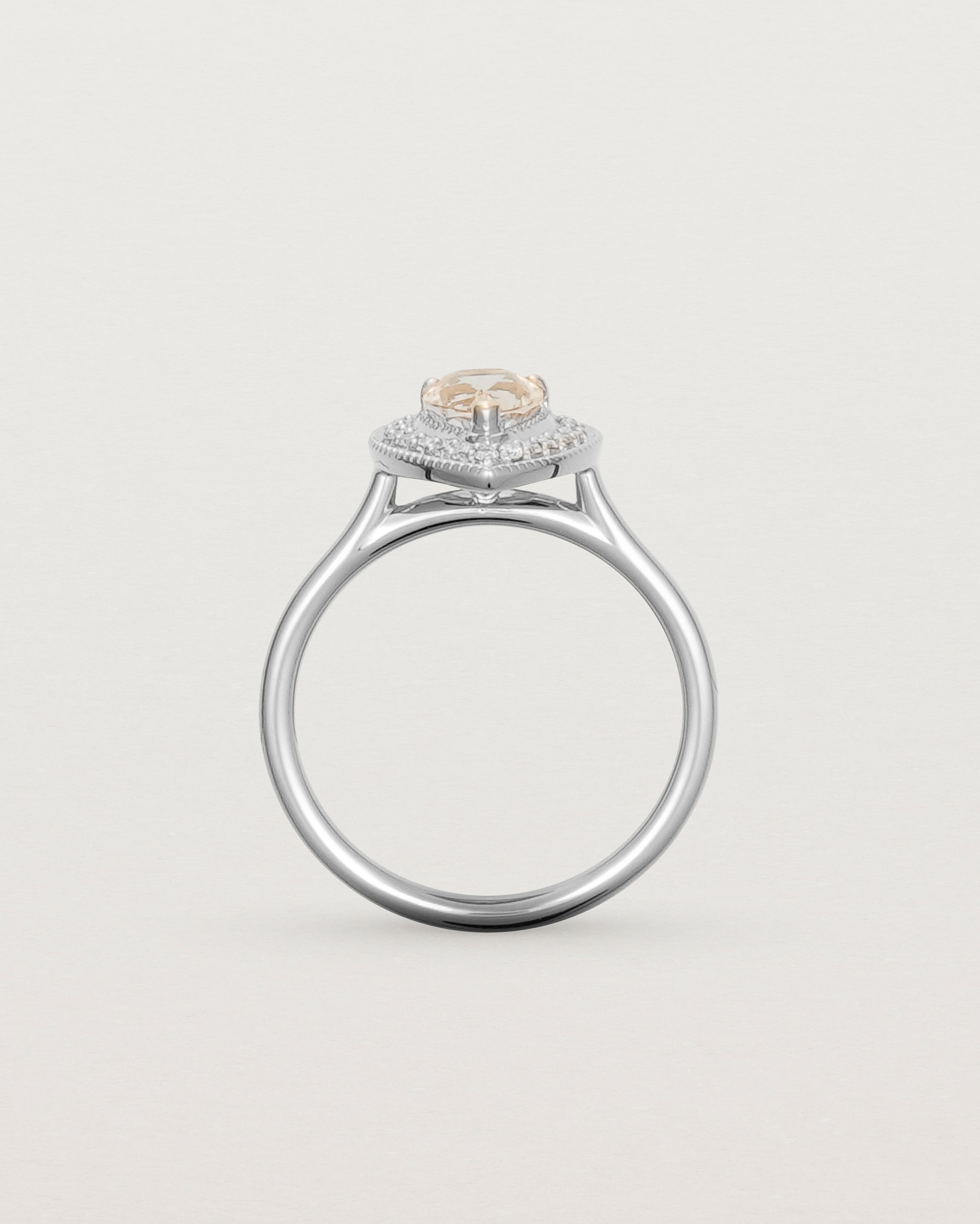 Standing view pear halo ring featuring a pear cut pale pink morganite and a halo of white diamonds in white gold
