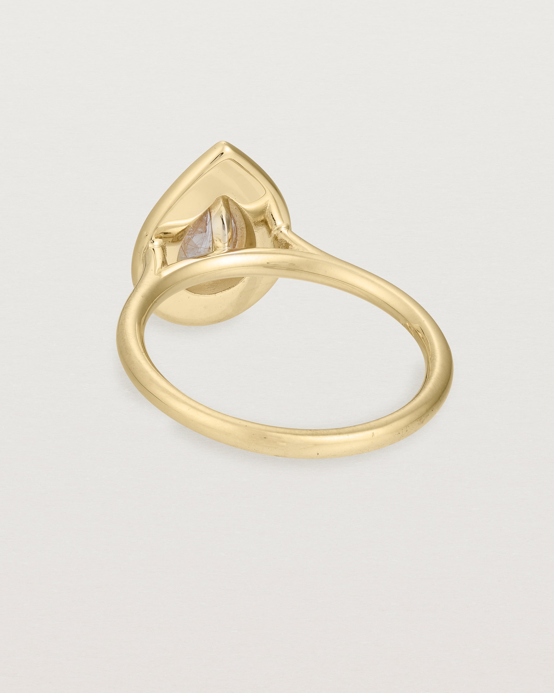 back view pear halo ring featuring a pear cut rutilated quartz stone and a halo of white diamonds in yellow gold