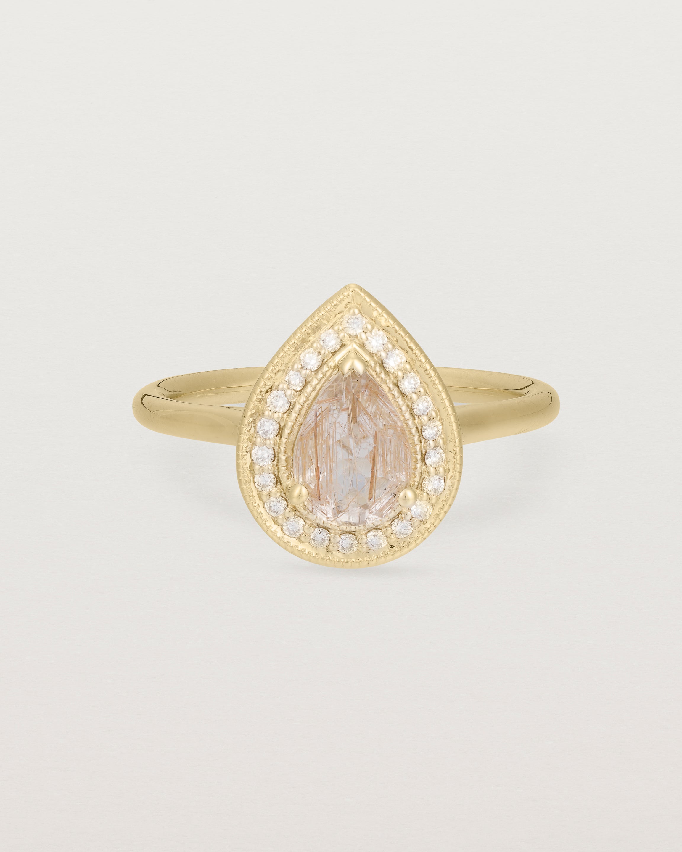 Front view pear halo ring featuring a pear cut rutilated quartz stone and a halo of white diamonds in yellow gold