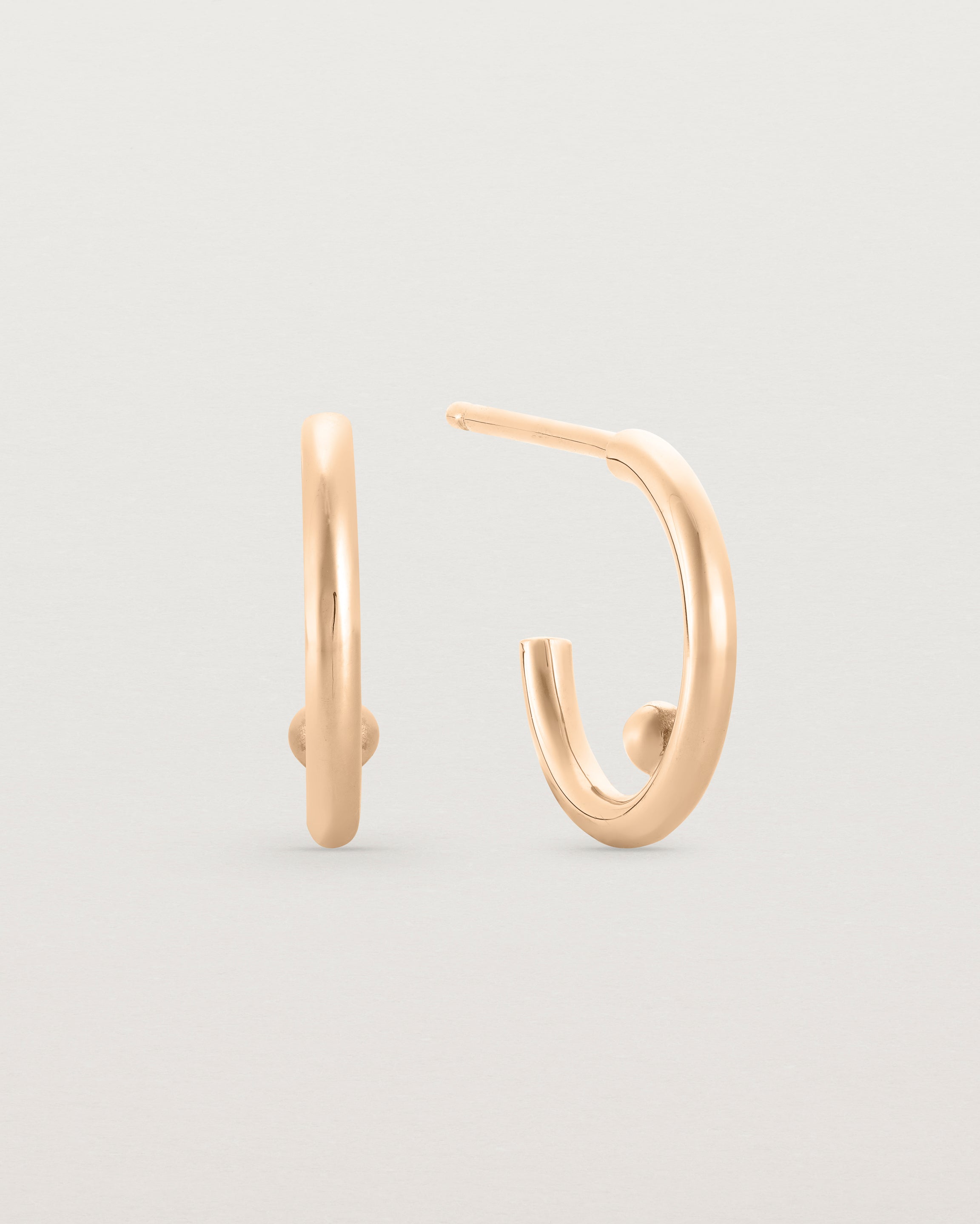 A small pair of rose gold open hoops with a gold ball in the centre