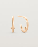 A small pair of rose gold open hoops with a gold ball in the centre