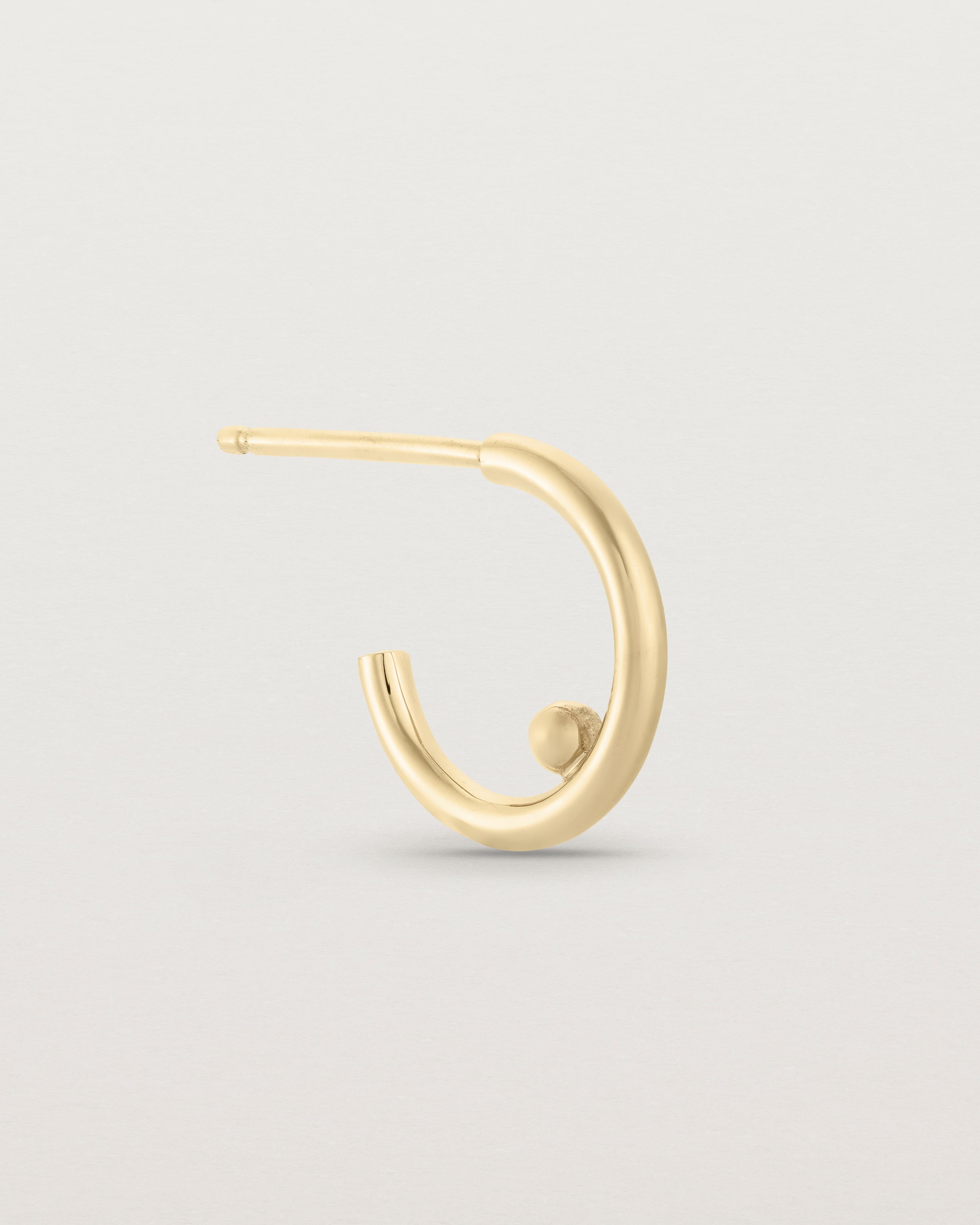 A small pair of yellow gold open hoops with a gold ball in the centre