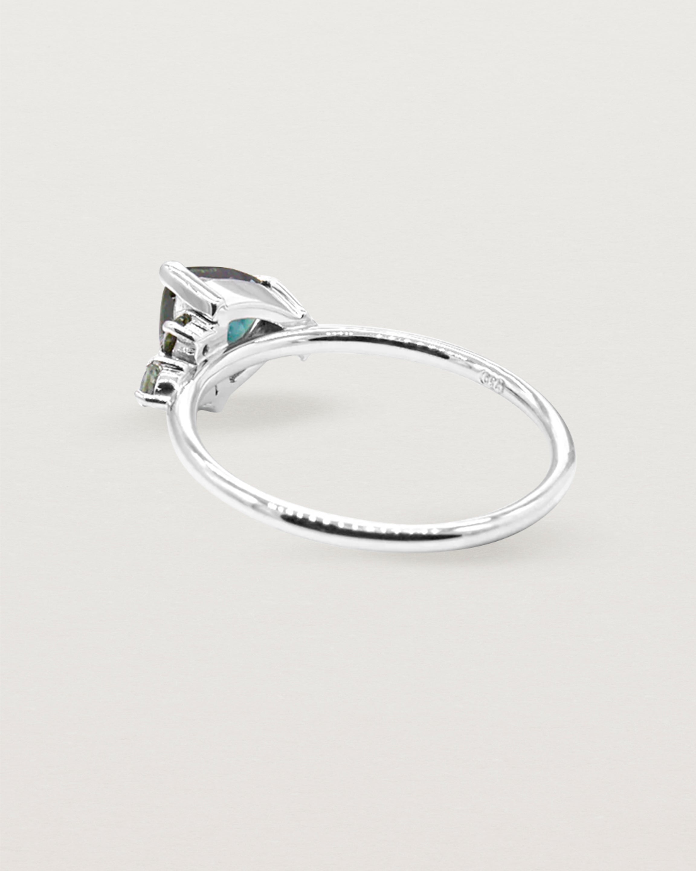 A distinctive cluster, featuring an iridescent trillion cut sapphire and crafted in white gold