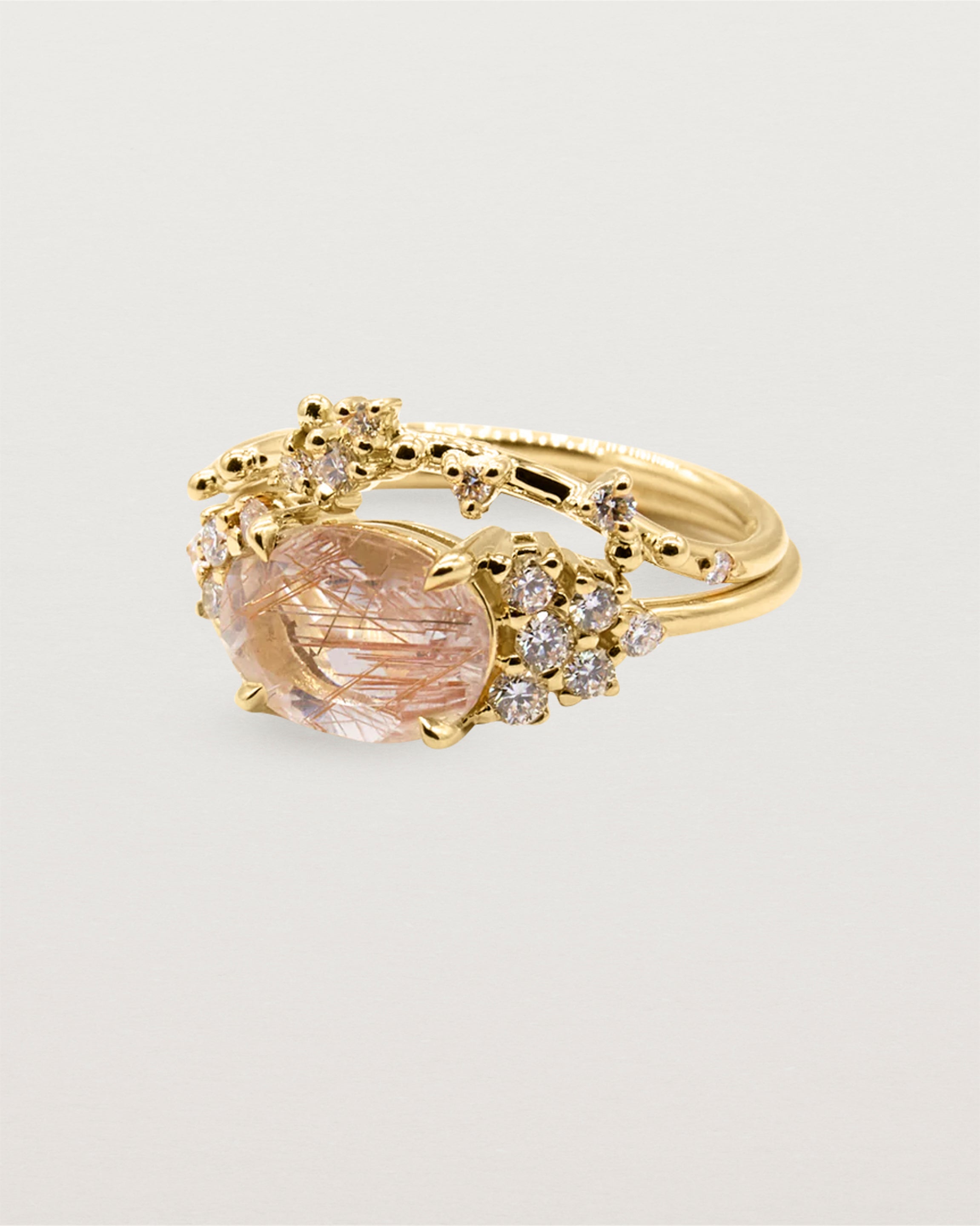 A bespoke gentle arc band feature a unique cluster of diamonds crafted in yellow gold and stacked with a rutilated quartz trio ring