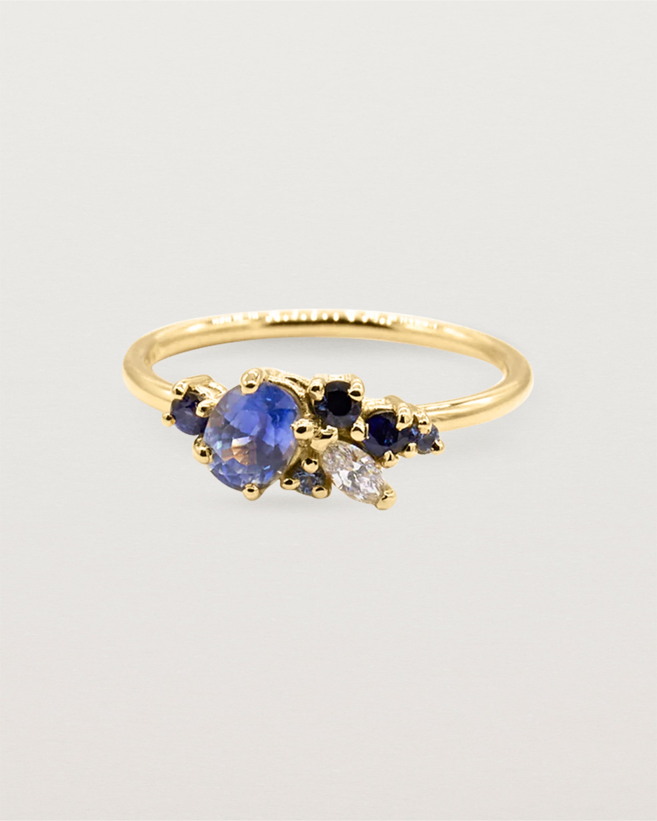 A diamond and sapphire cluster ring, featuring oval marquise and round stones, crafted in 18ct yellow gold