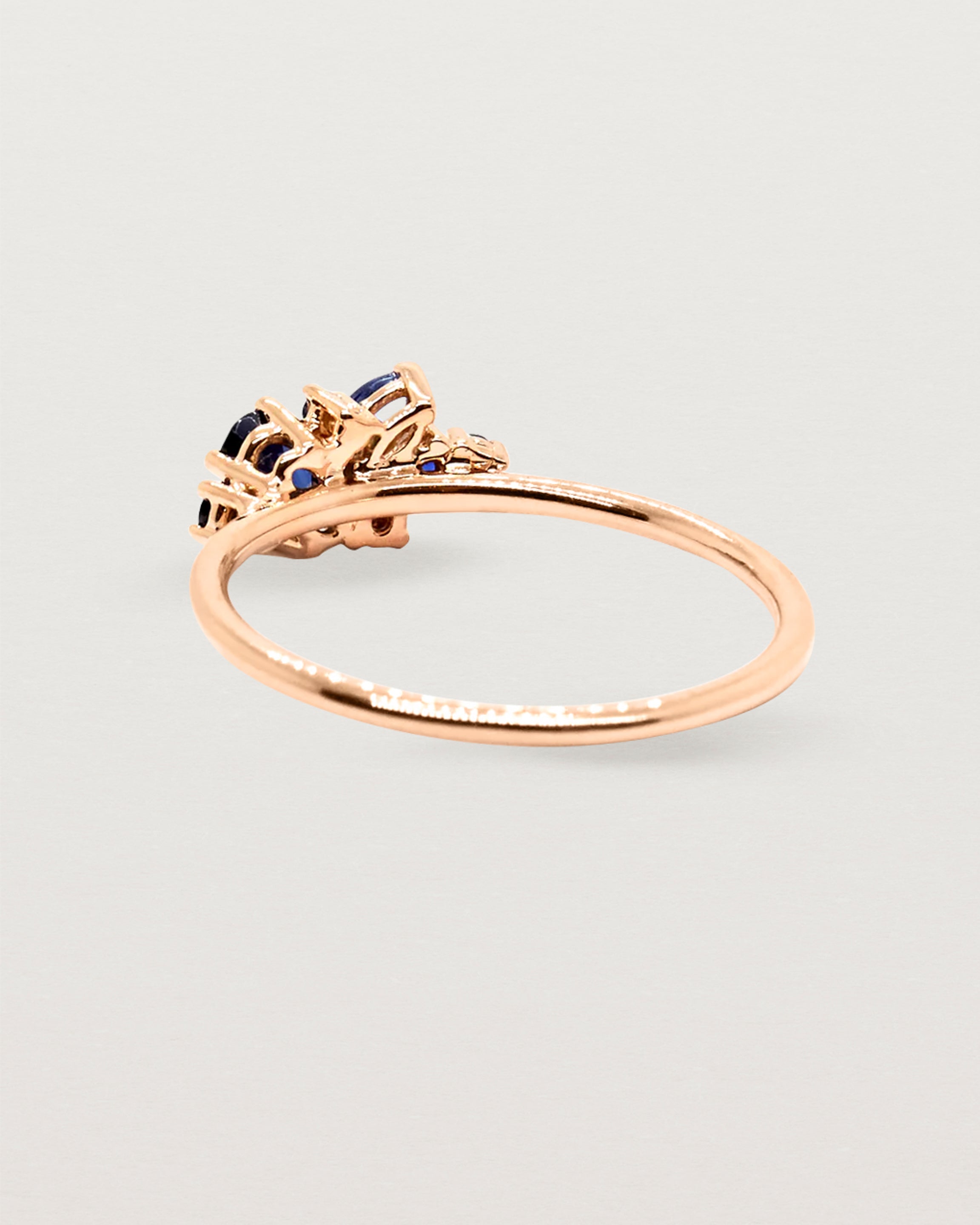 Deep blue sapphire cluster ring, featuring marquise, oval and round stones, crafted in rose gold