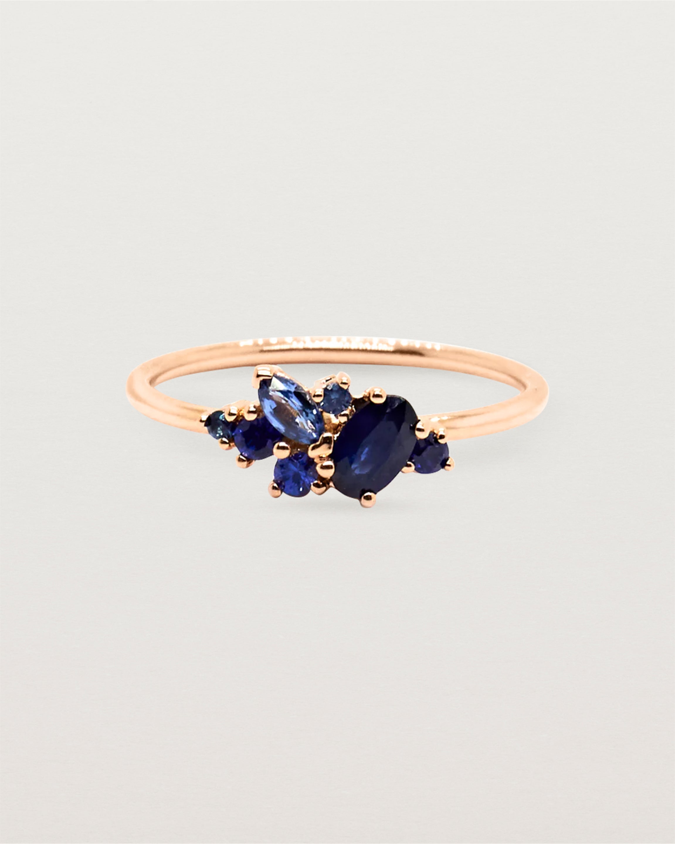 Deep blue sapphire cluster ring, featuring marquise, oval and round stones, crafted in rose gold