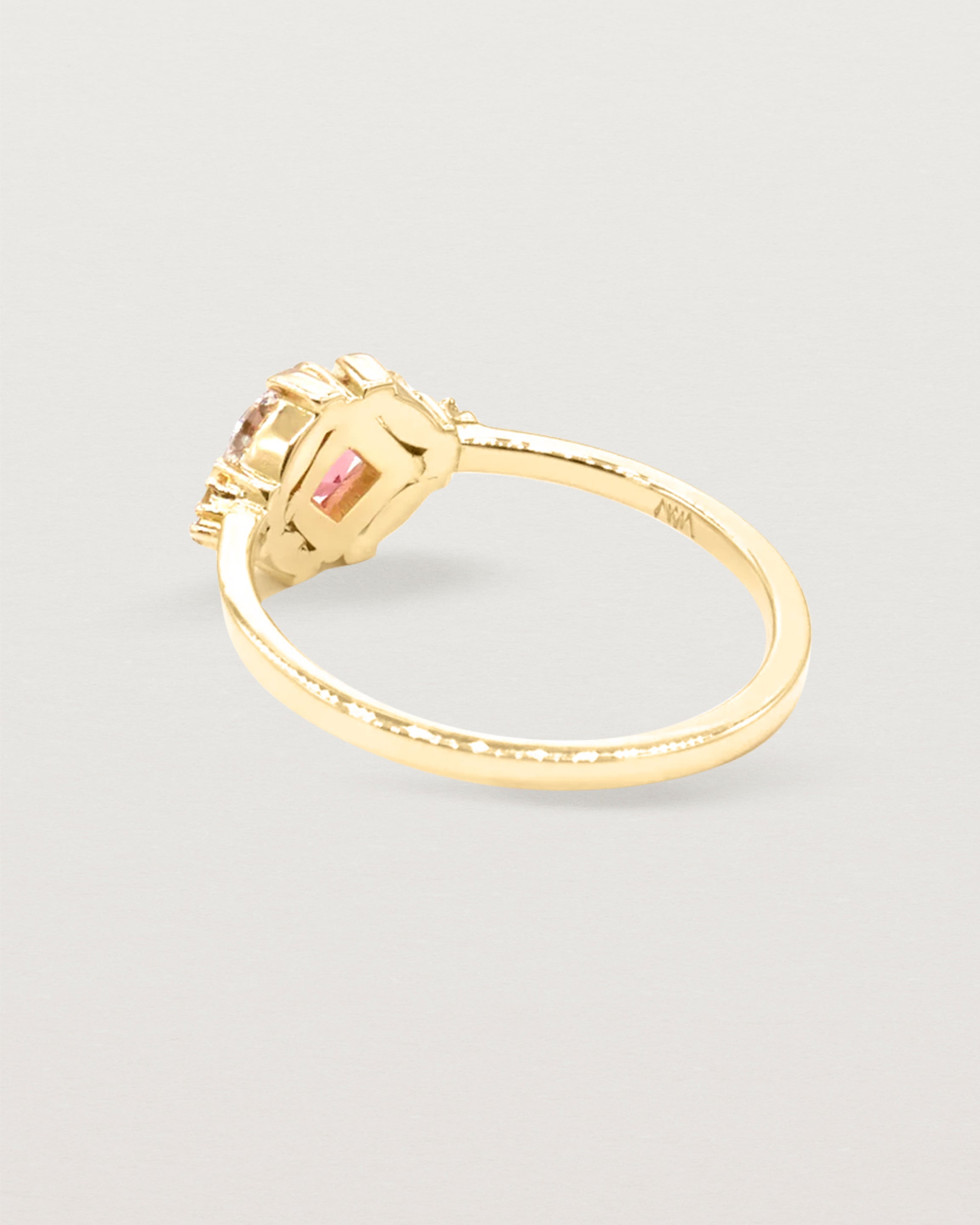 The back view of an asscher cut pink spinel is heroes by white diamond clusters set in yellow gold.
