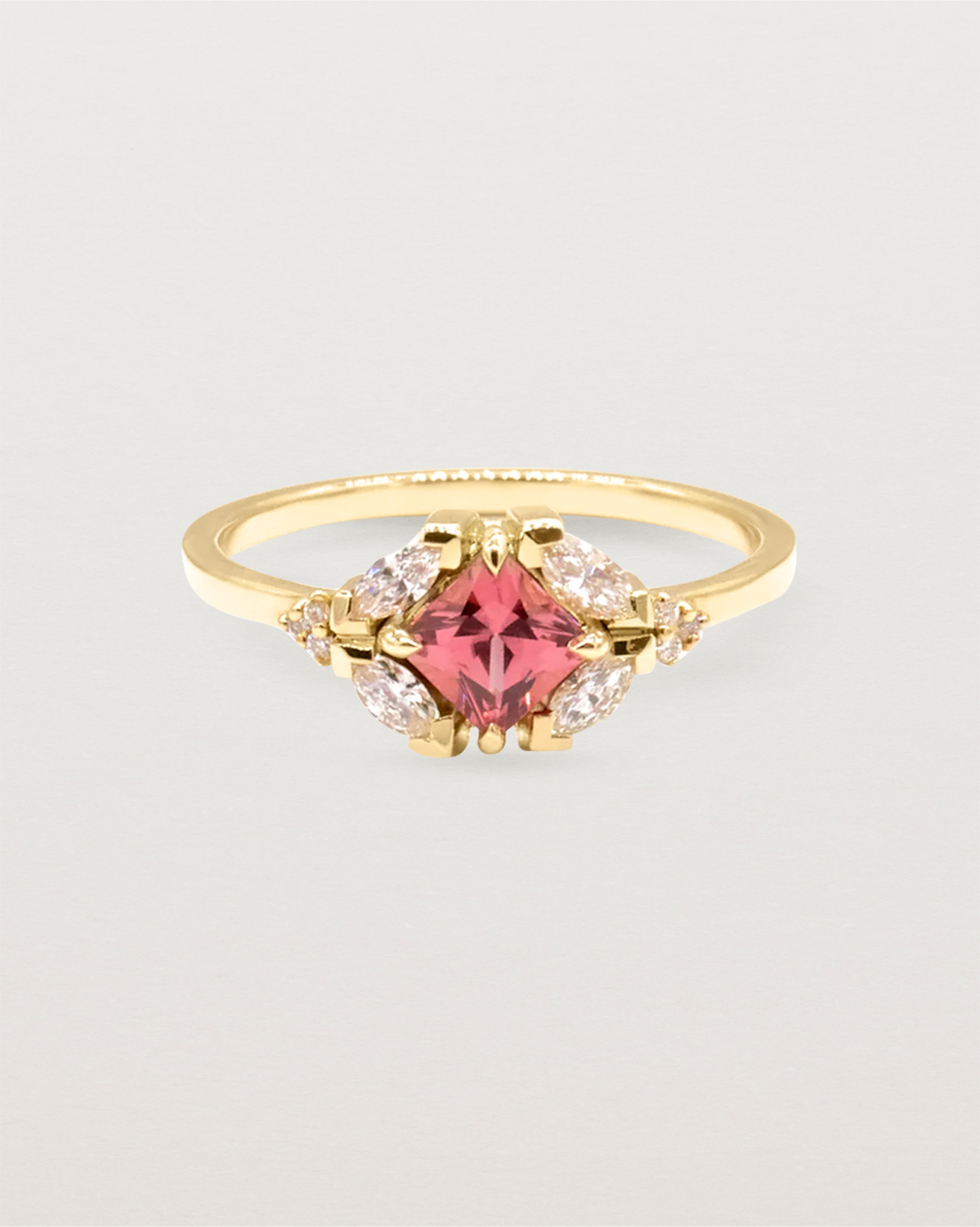An asscher cut pink spinel is heroes by white diamond clusters set in yellow gold.