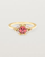 An asscher cut pink spinel is heroes by white diamond clusters set in yellow gold.