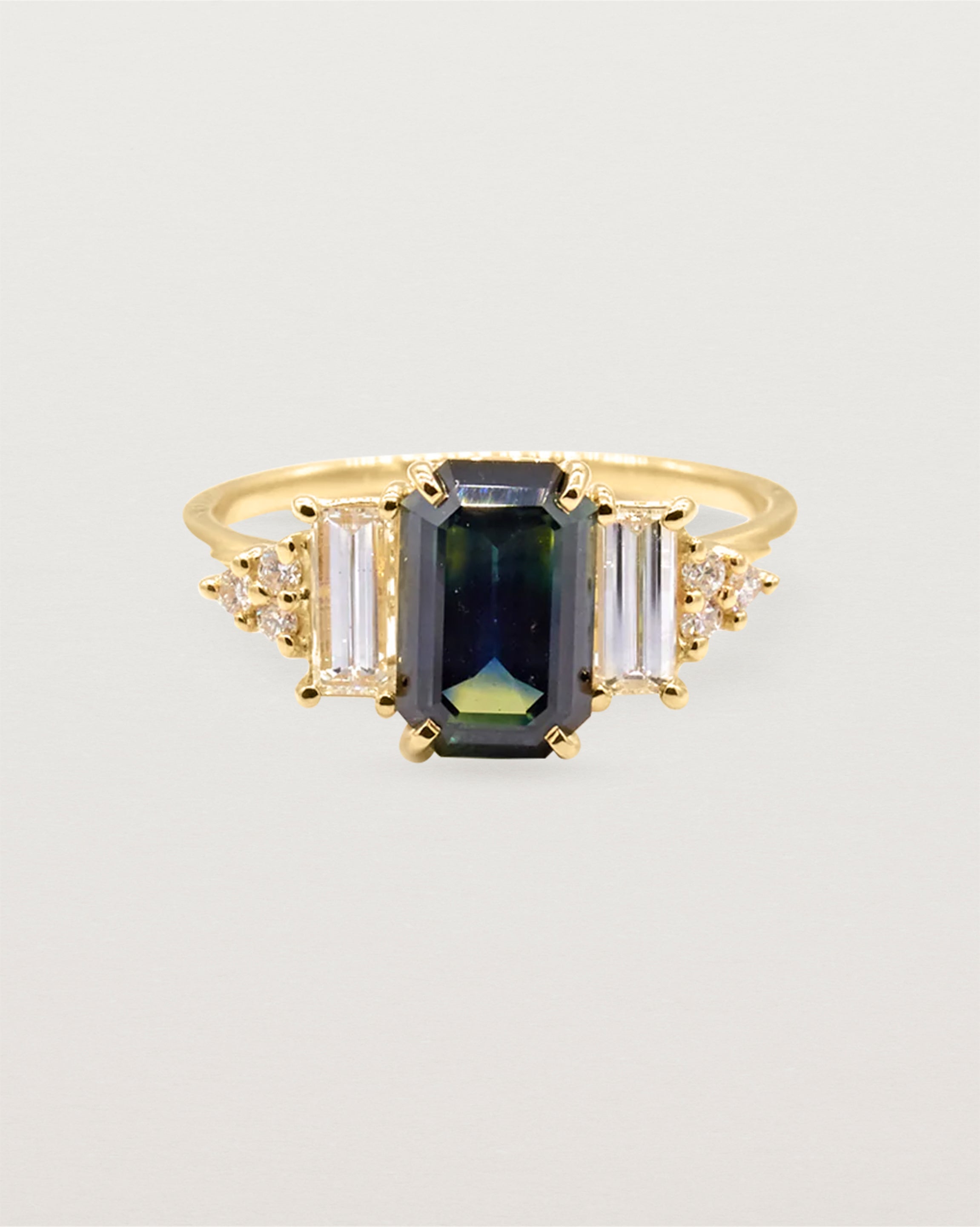 A 2.56ct Australian parti sapphire, set amongst a vintage inspired baguette and round cut diamond cluster crafted in yellow gold.