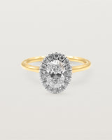 A 0.70ct oval cut diamond is adorned with a sparkling white diamond halo crafted in both yellow gold and white gold 