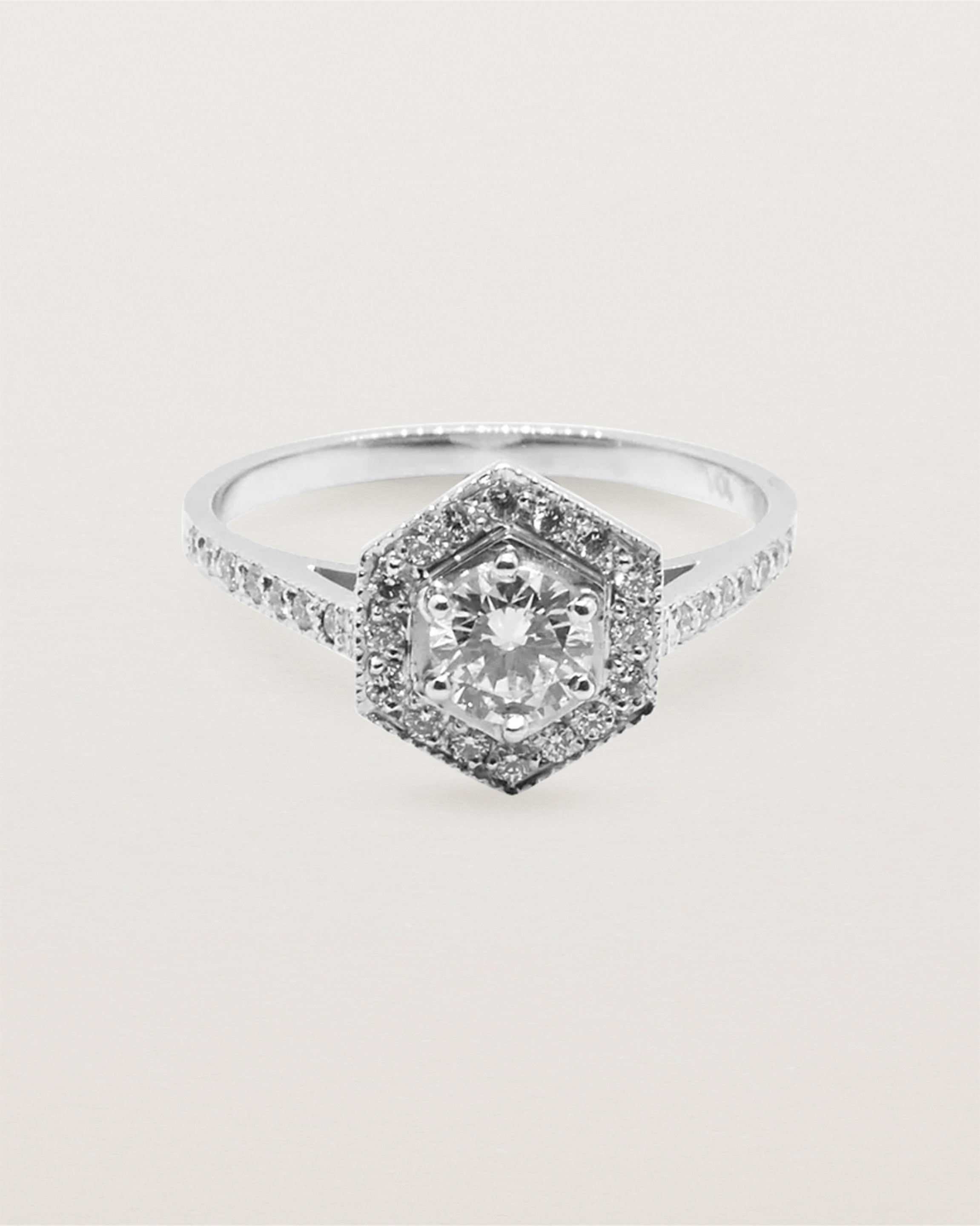 A hexagonal halo diamond ring featuring a central 0.32 carat round cut diamond and surrounded by a diamond halo.