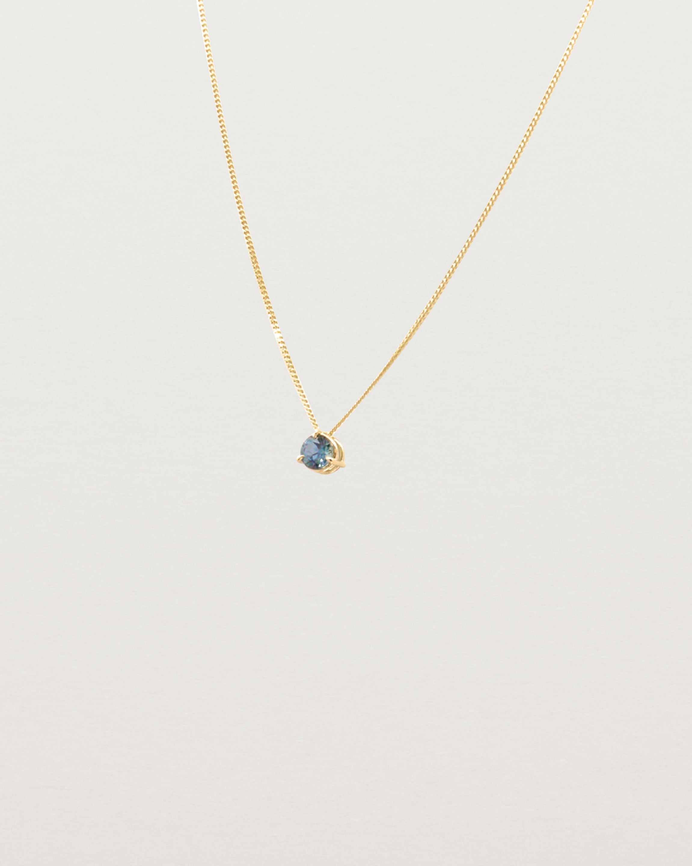 A 3mm blue sapphire is set simply on a fine chain. 