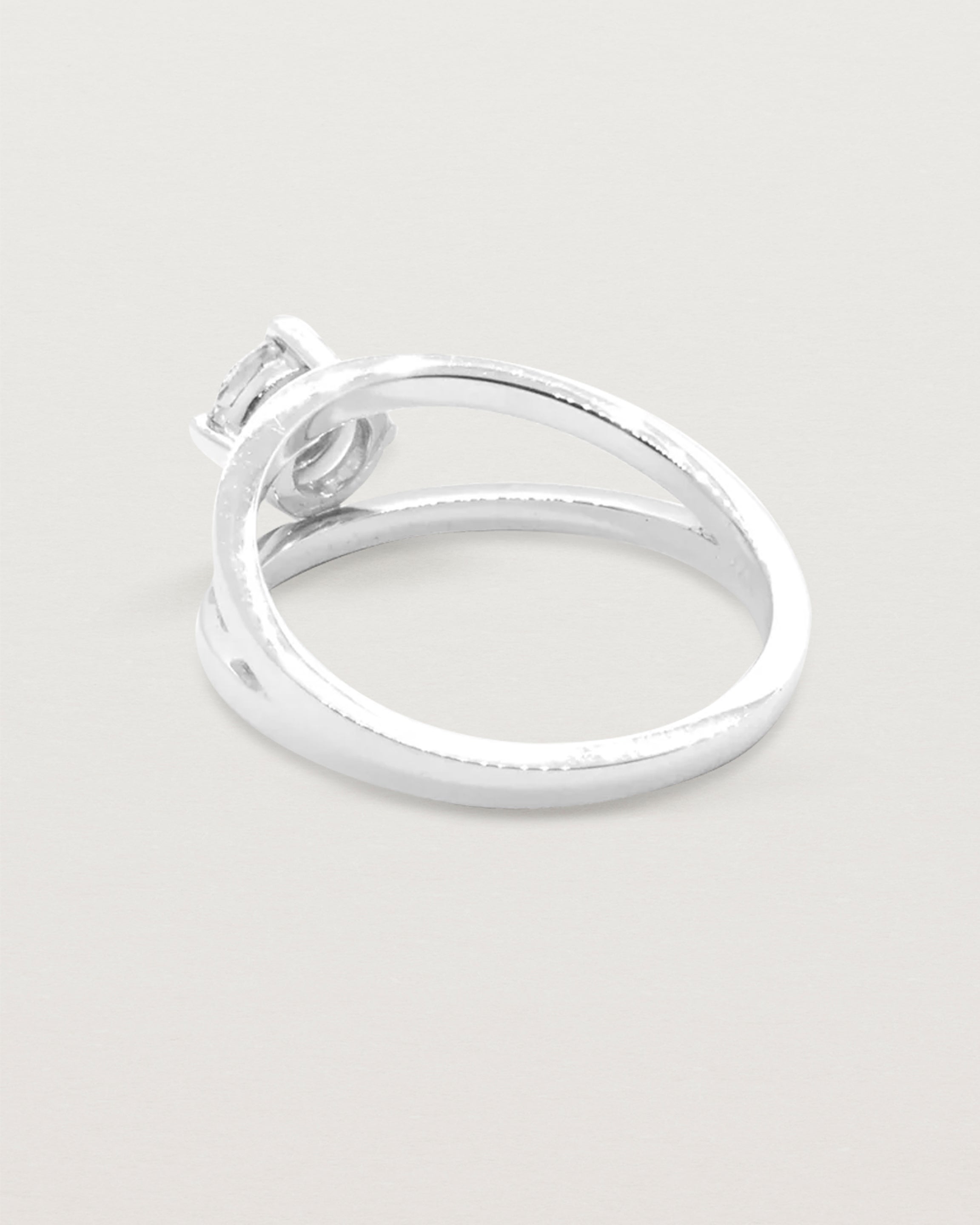 A square profile double-band sweeps up to hold a round brilliant cut white diamond, crafted in white gold