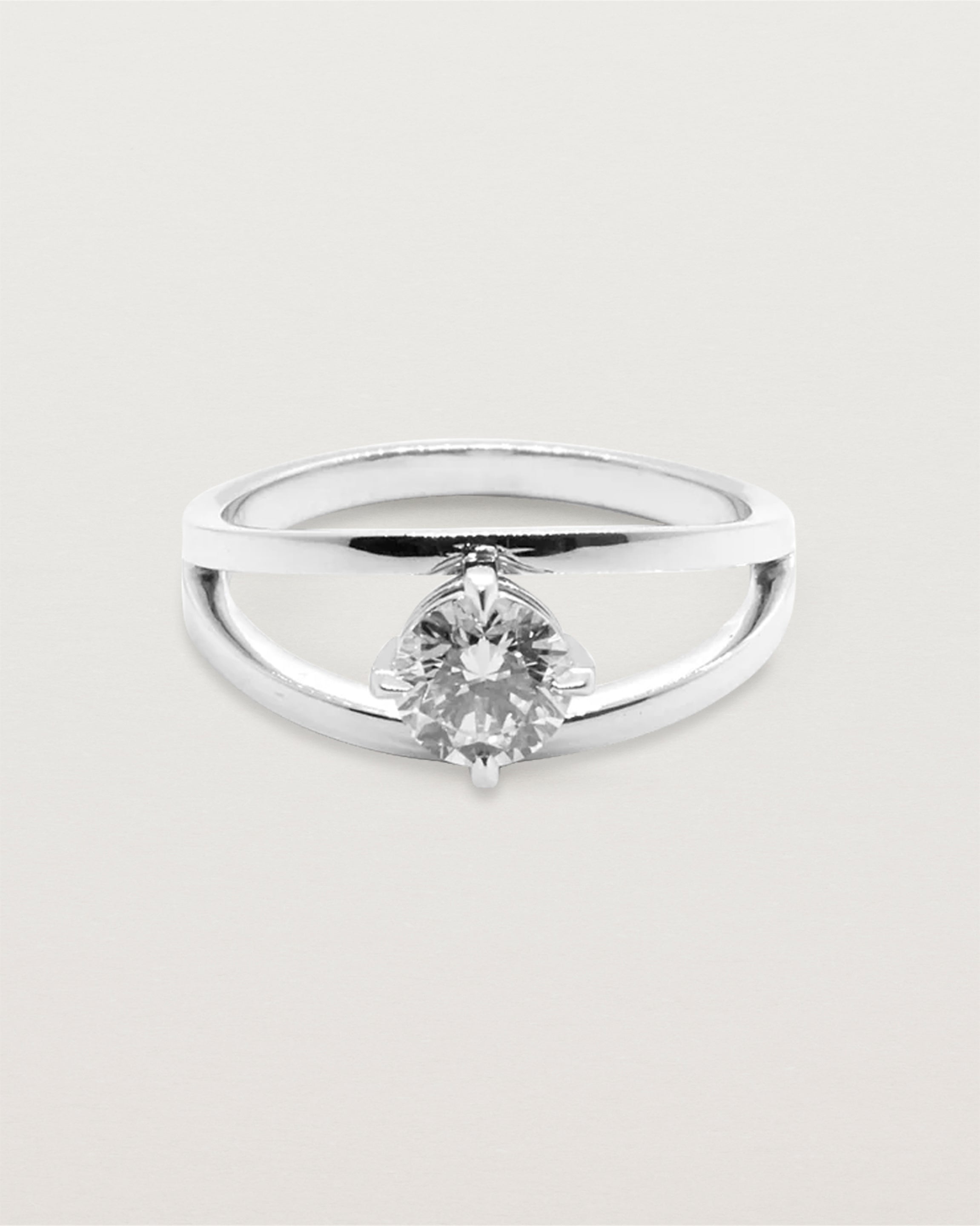 A square profile double-band sweeps up to hold a round brilliant cut white diamond, crafted in white gold