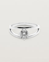 A square profile double-band sweeps up to hold a round brilliant cut white diamond, crafted in white gold
