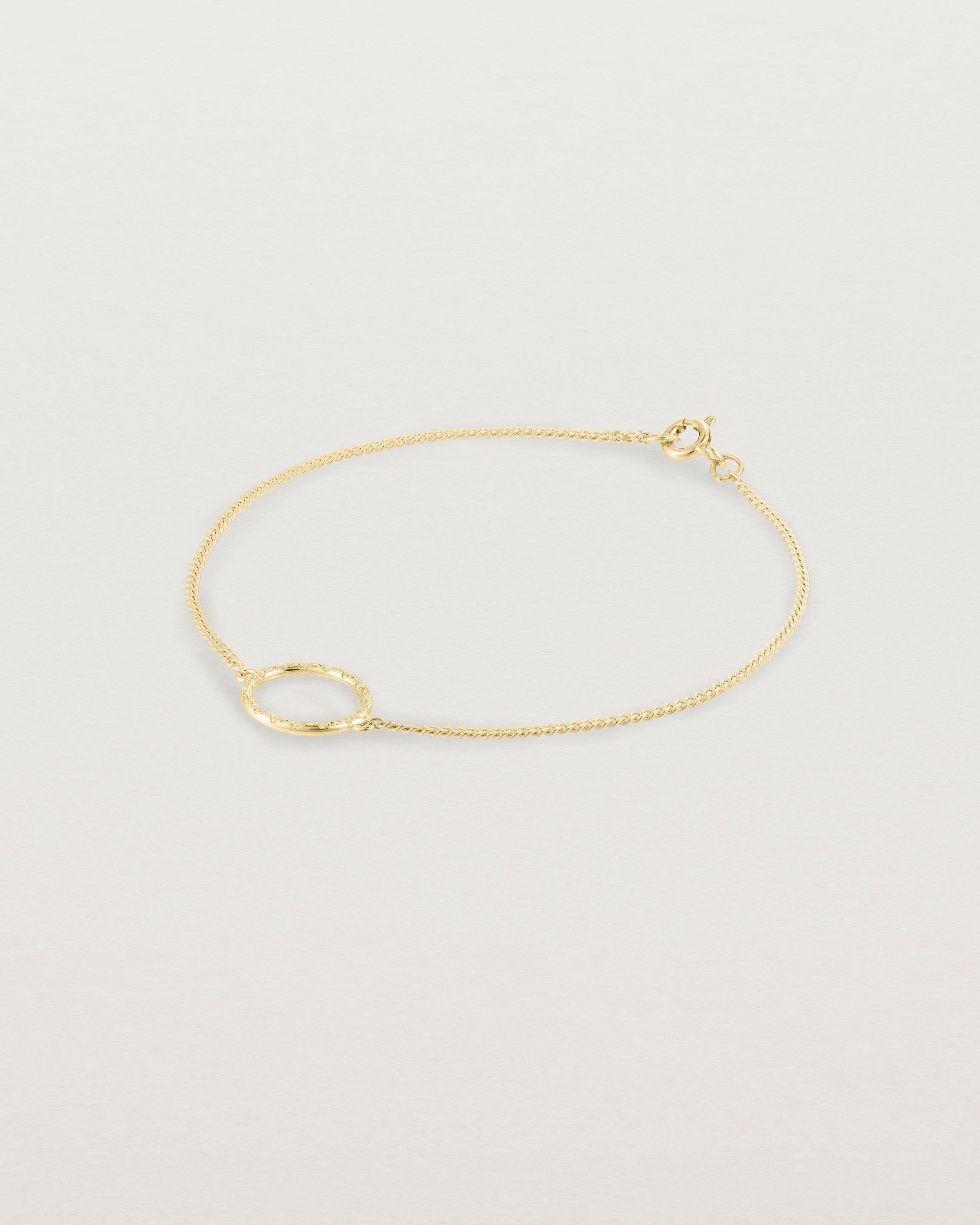 A white gold chain bracelet featuring a gold circle set with small white diamonds