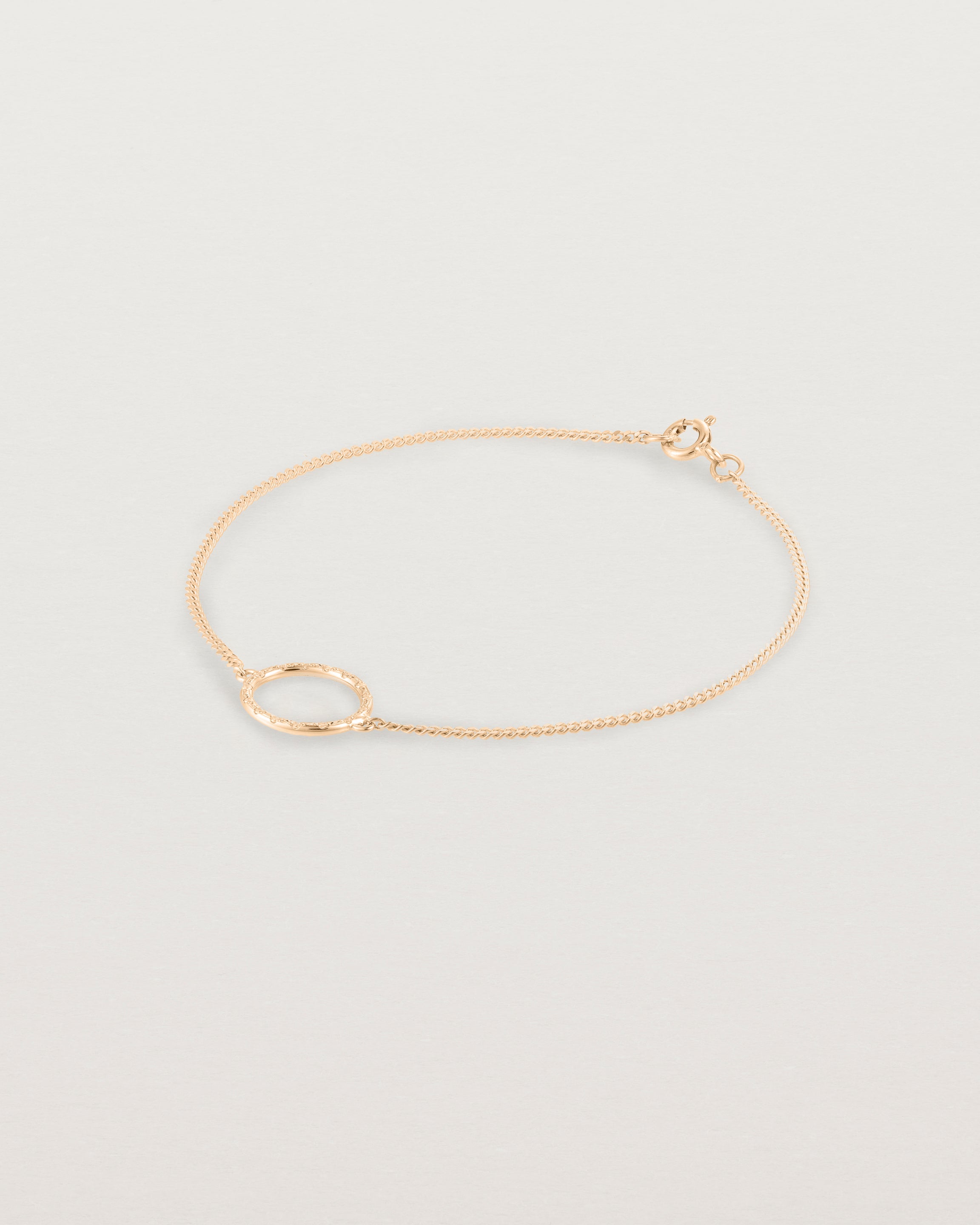 A rose gold chain bracelet featuring a circle set with small white diamonds