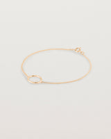 A rose gold chain bracelet featuring a circle set with small white diamonds