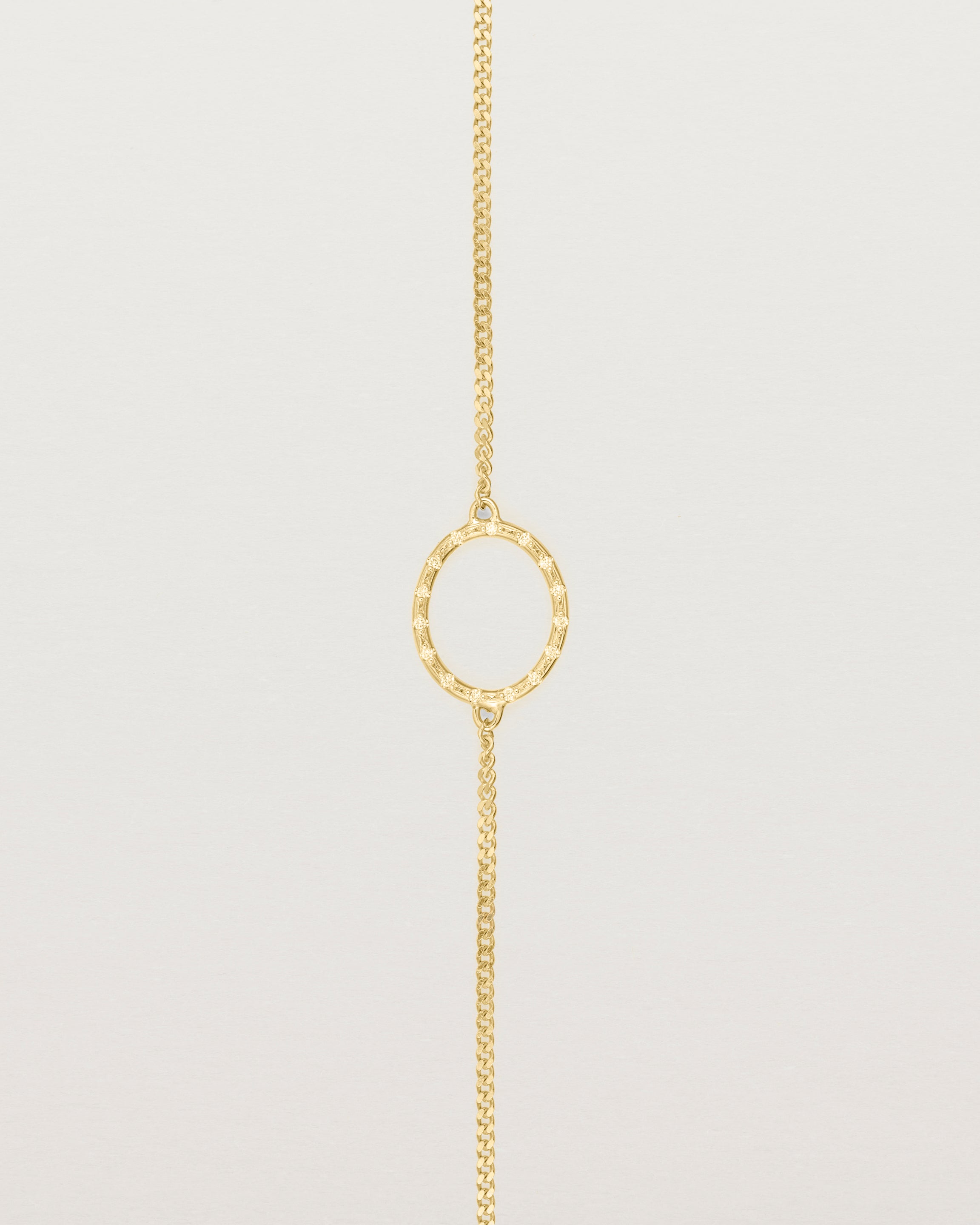 A white gold chain bracelet featuring a gold circle set with small white diamonds