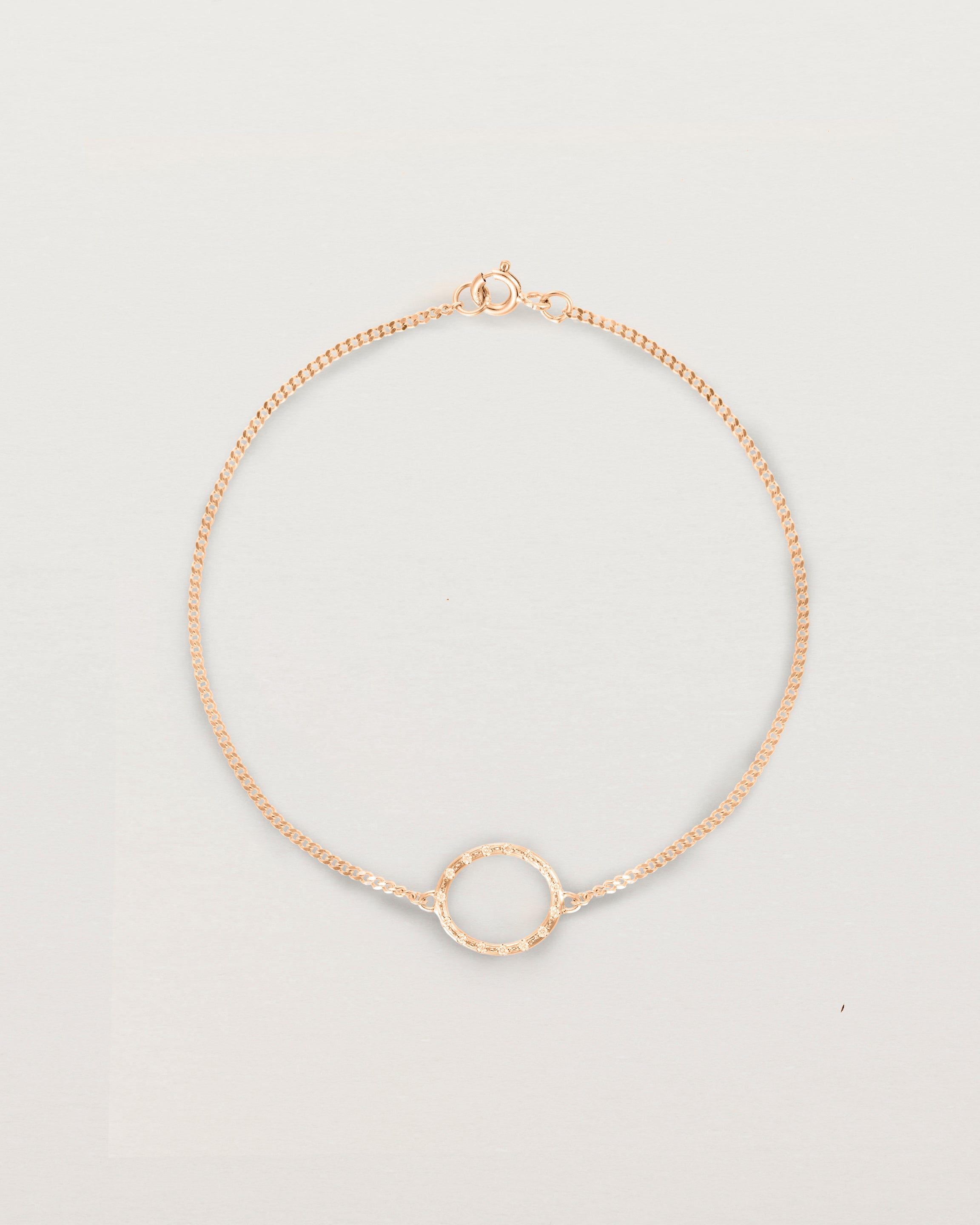 A rose gold chain bracelet featuring a circle set with small white diamonds