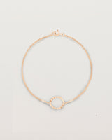 A rose gold chain bracelet featuring a circle set with small white diamonds