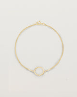 A white gold chain bracelet featuring a gold circle set with small white diamonds