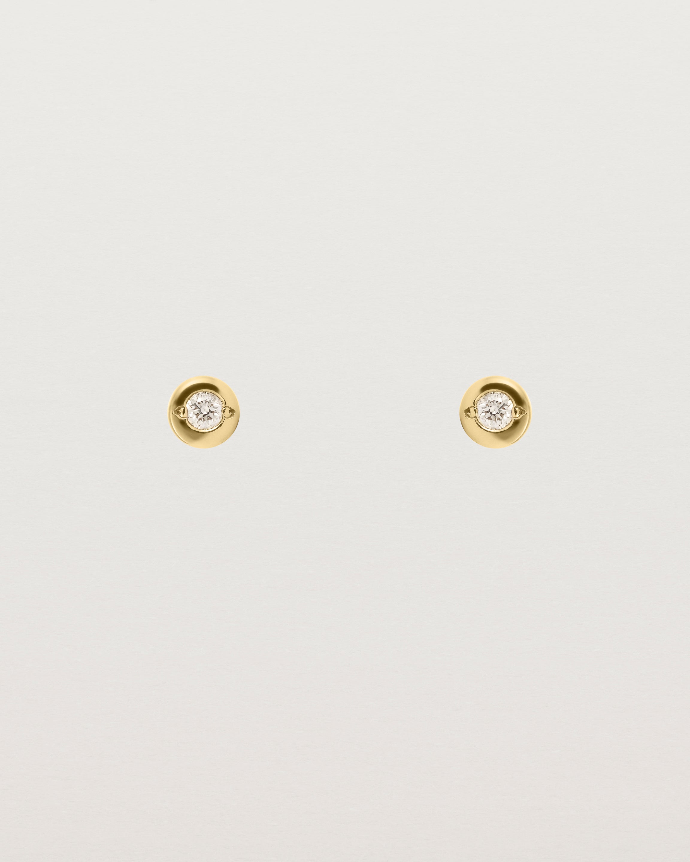 A small white circular yellow gold stud featuring a white diamond