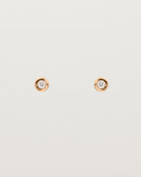 A small white circular rose gold stud featuring a white diamond