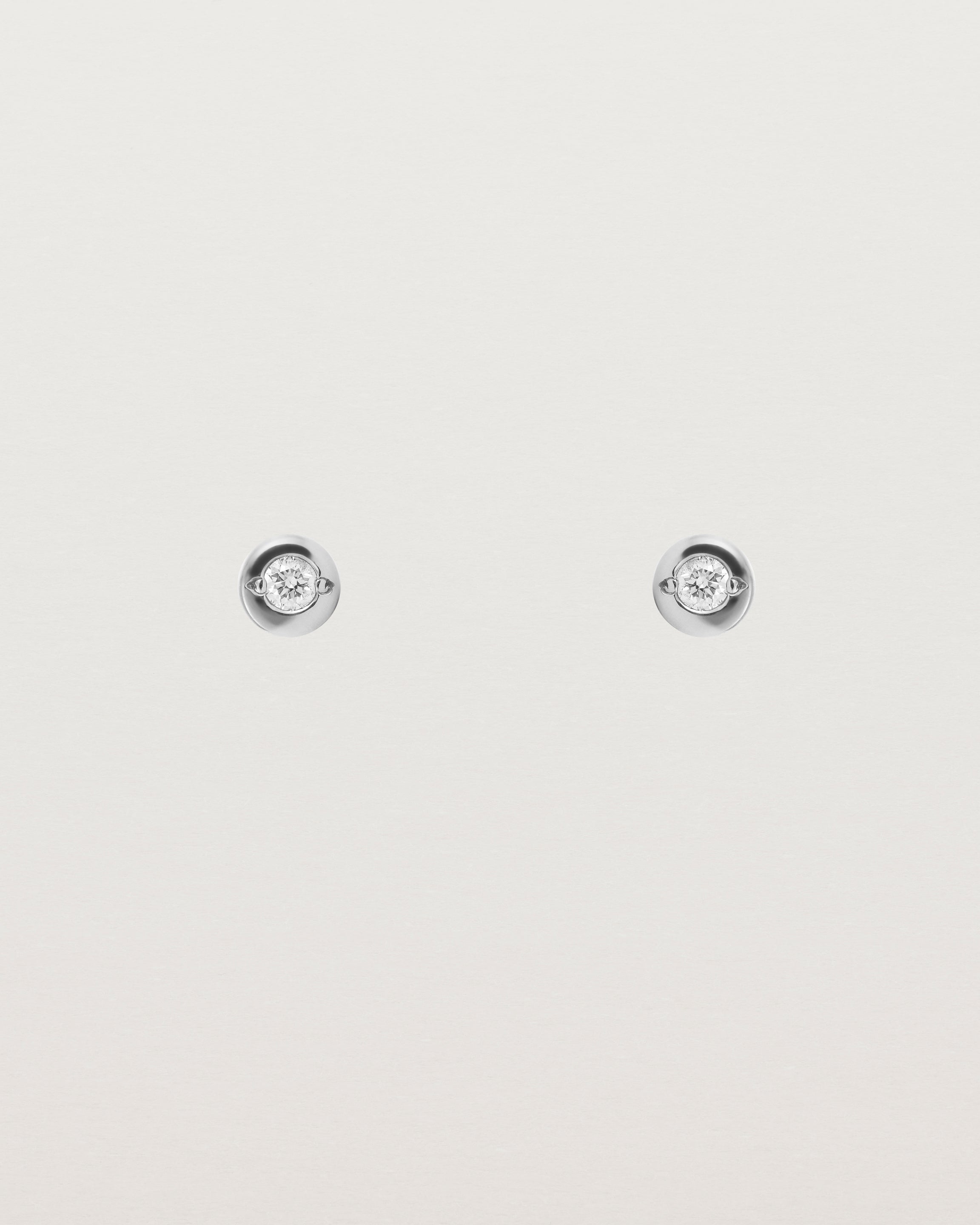 A small circular white gold stud featuring a white diamond