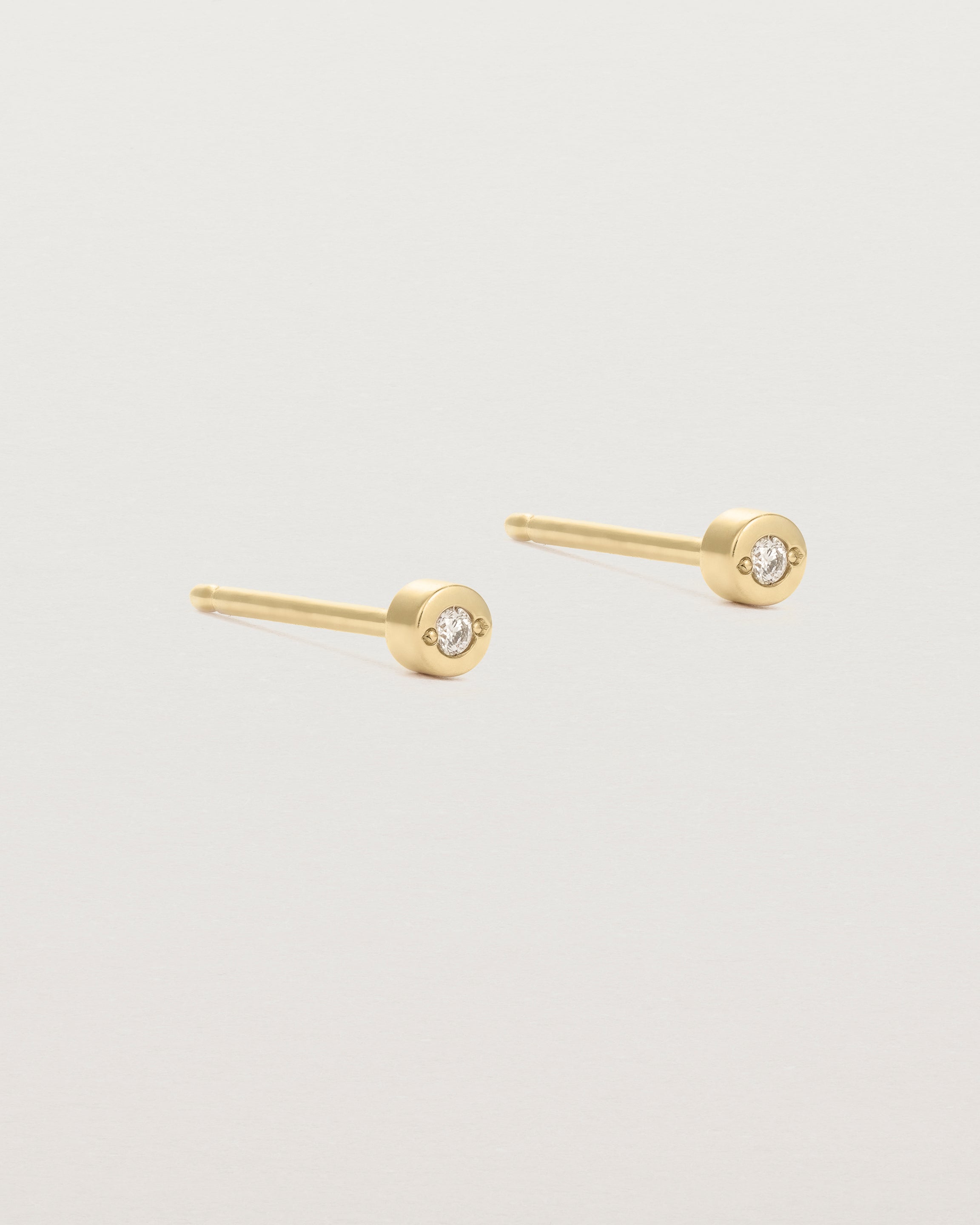 A small white circular yellow gold stud featuring a white diamond