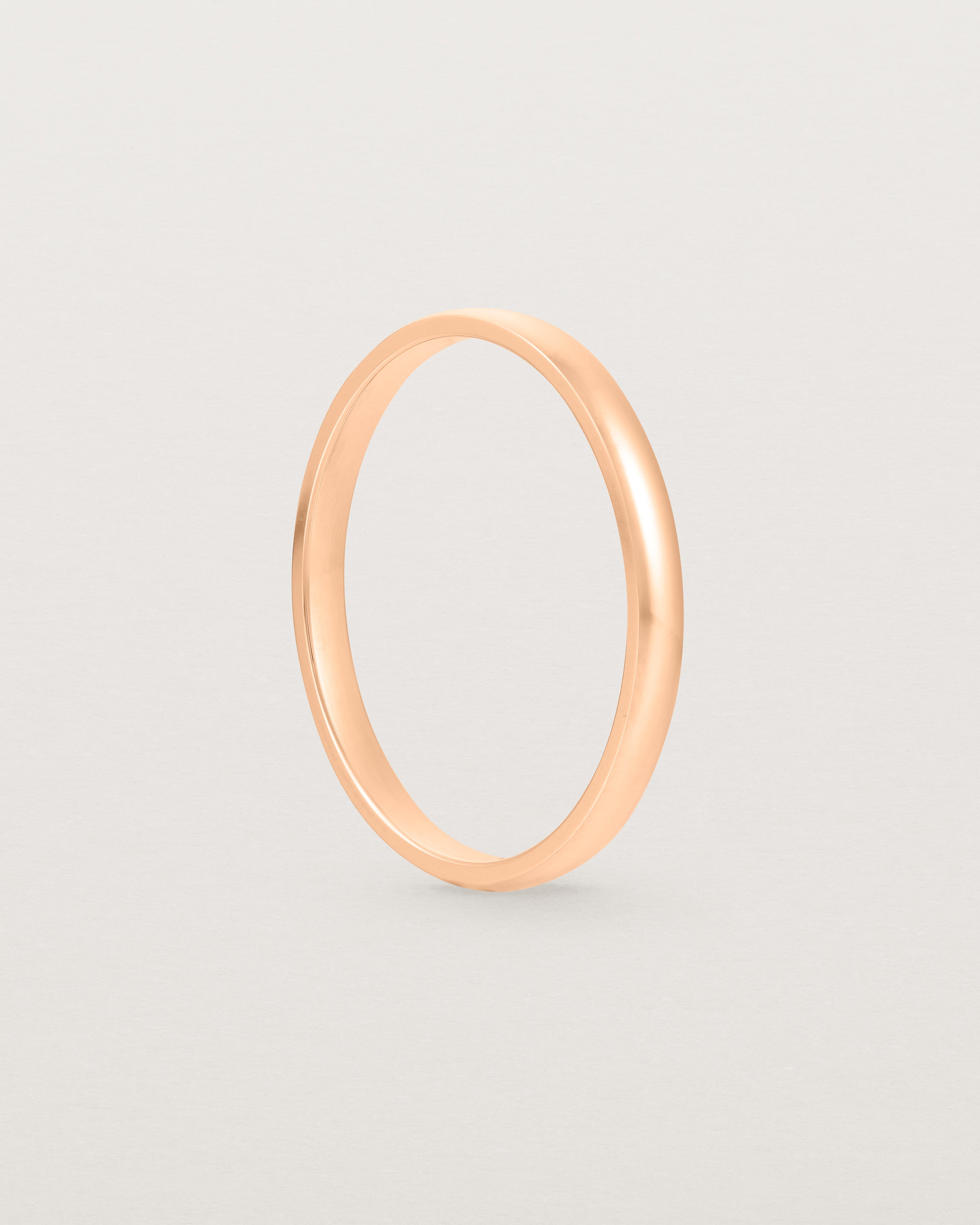 A fine classic wedding band in rose gold, side view