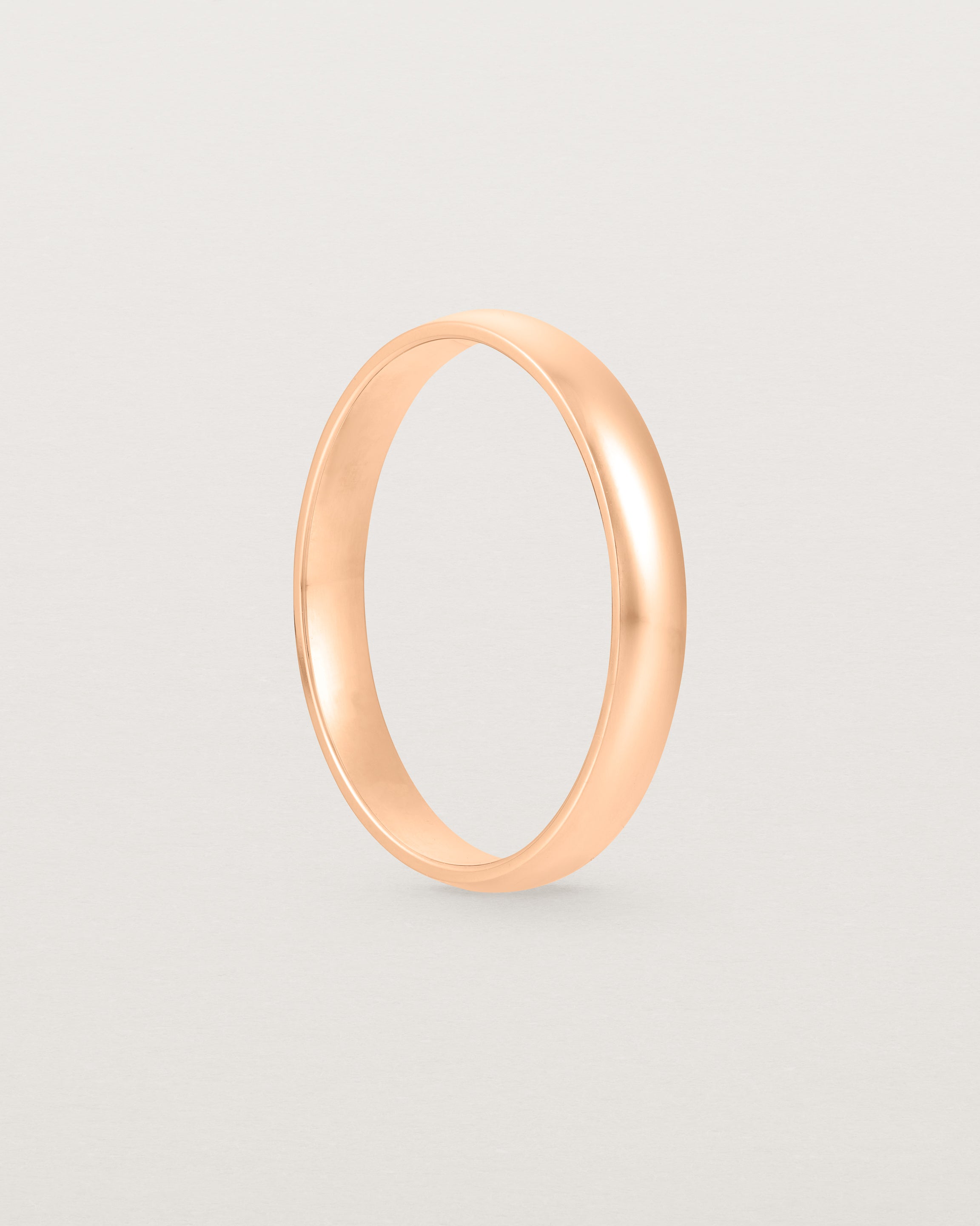 The side view of a 3mm fine, classic wedding band in rose gold.