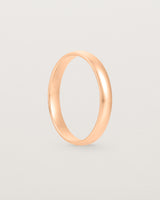 The side view of a 3mm fine, classic wedding band in rose gold.