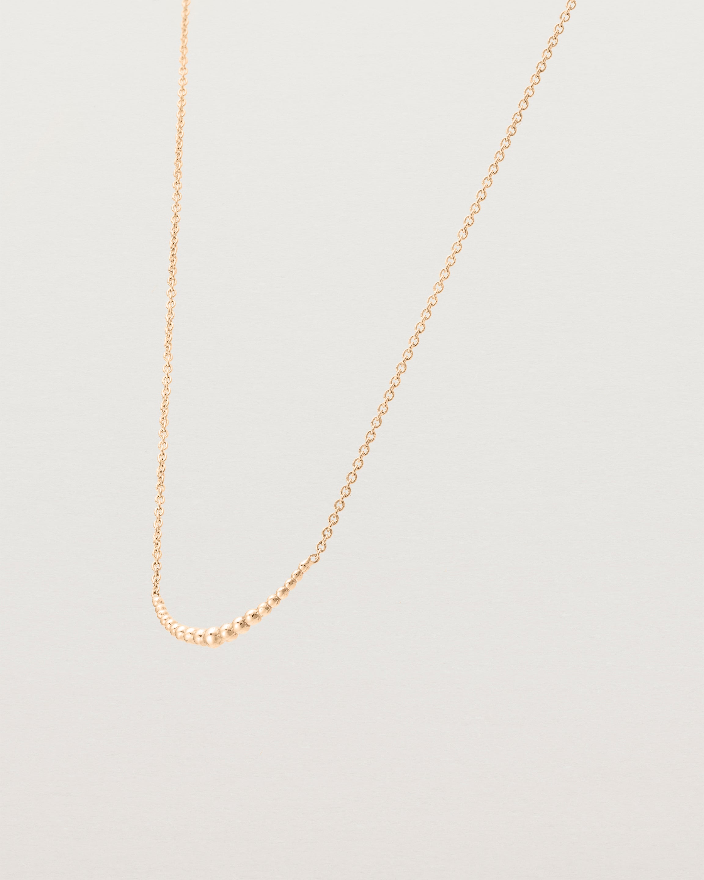 Angled view of the Crescent Necklace in Rose Gold.