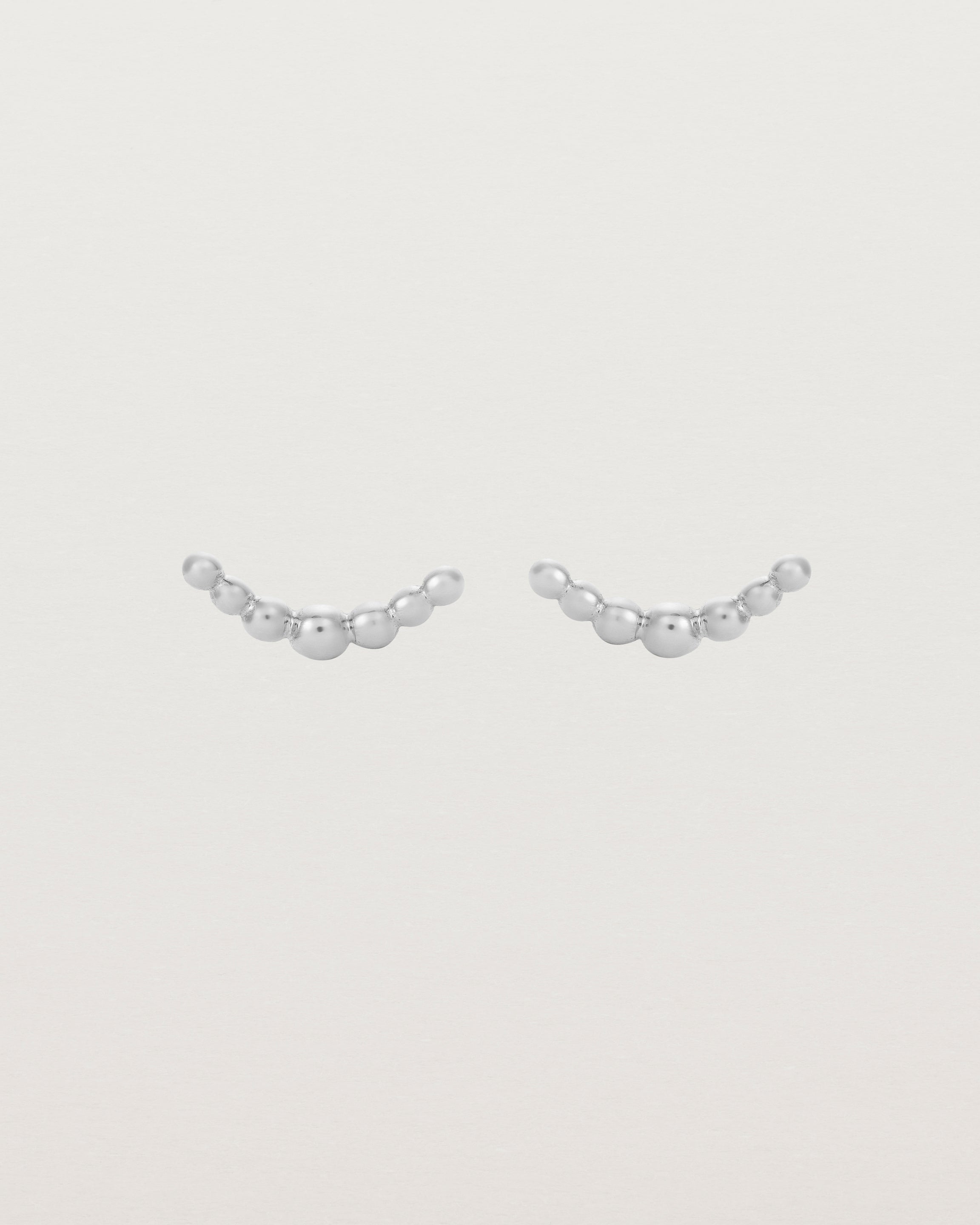 A pair of sterling silver studs featuring an arc of round metal balls