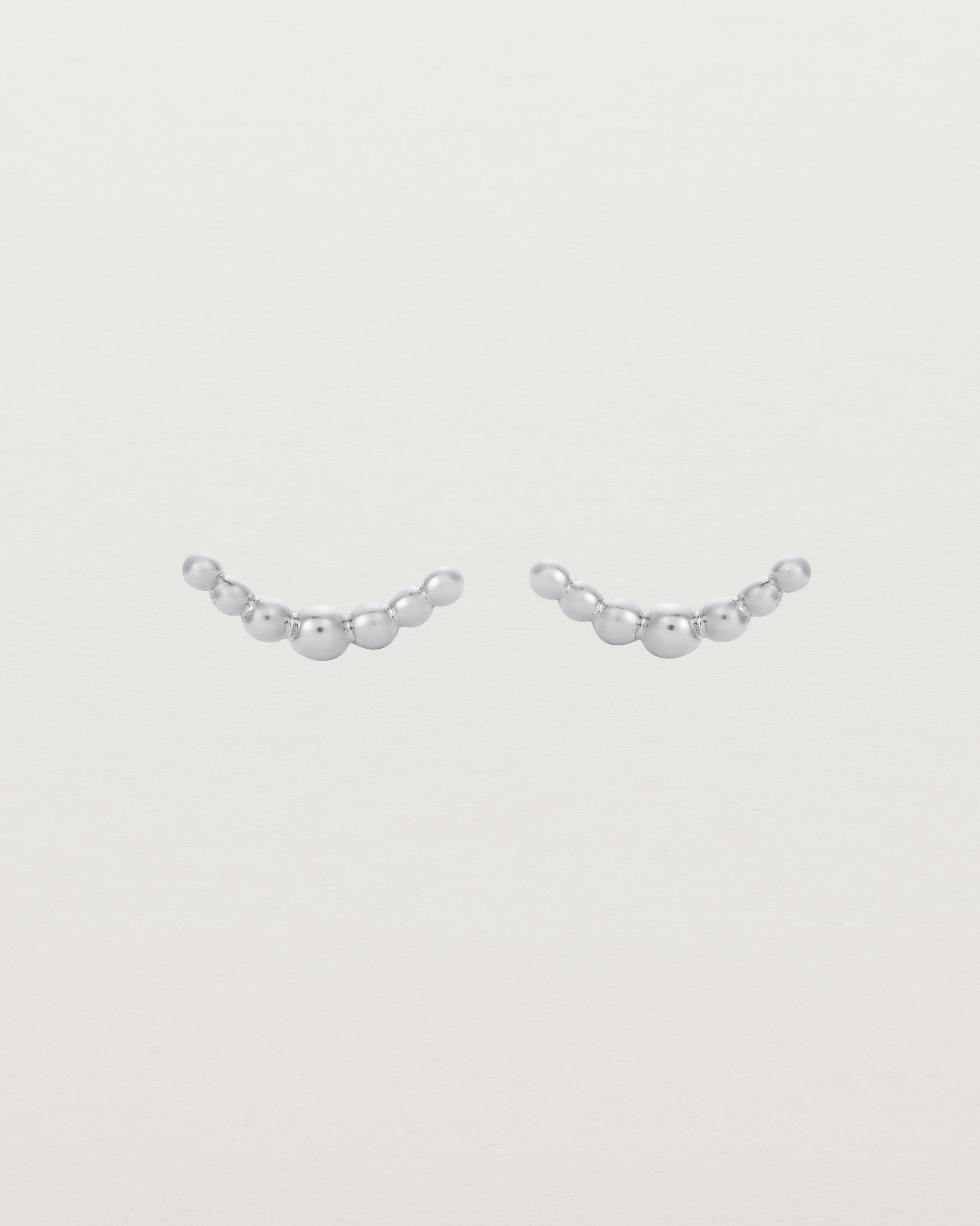 A pair of sterling silver studs featuring an arc of round metal balls