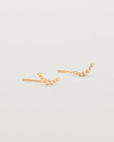 A pair of rose gold studs featuring an arc of round metal balls