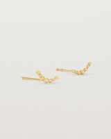 A pair of yellow gold studs featuring an arc of round metal balls