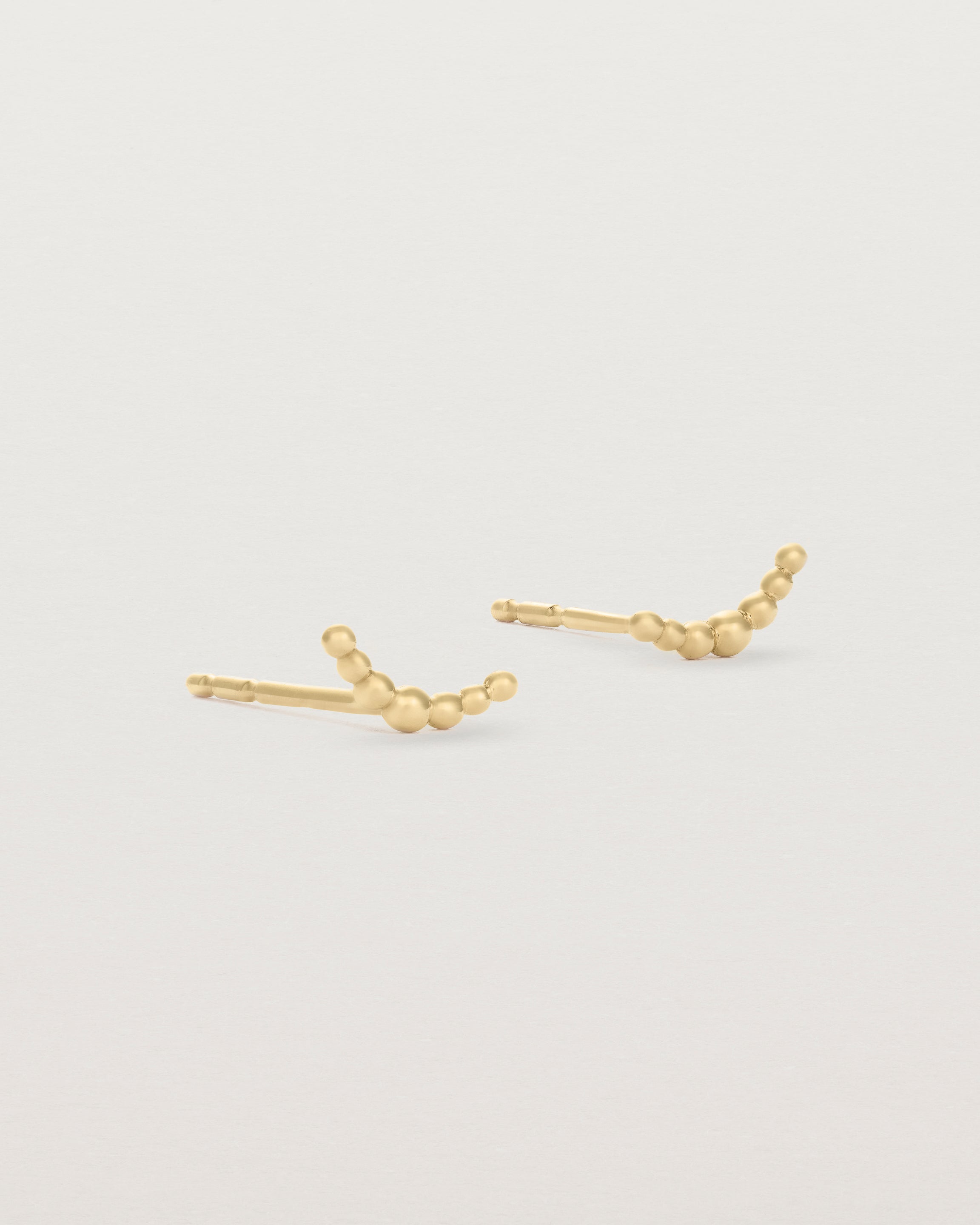 A pair of yellow gold studs featuring an arc of round metal balls