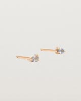 A pair of rose gold studs featuring a pear cut pale blue sapphire