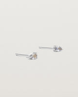 A pair of white gold studs featuring a pear cut pale blue sapphire