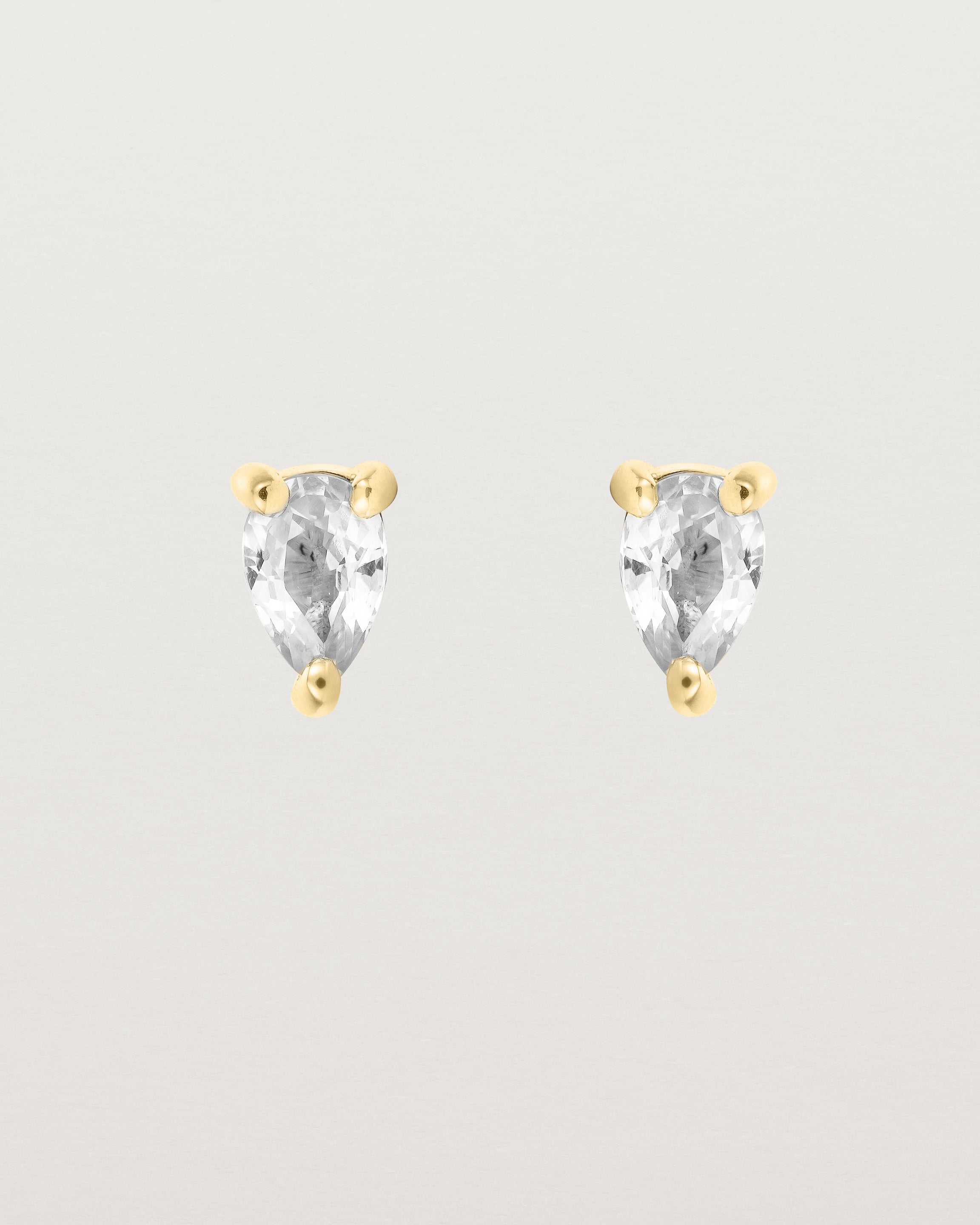 a pair of yellow gold studs featuring a pear cut diamond